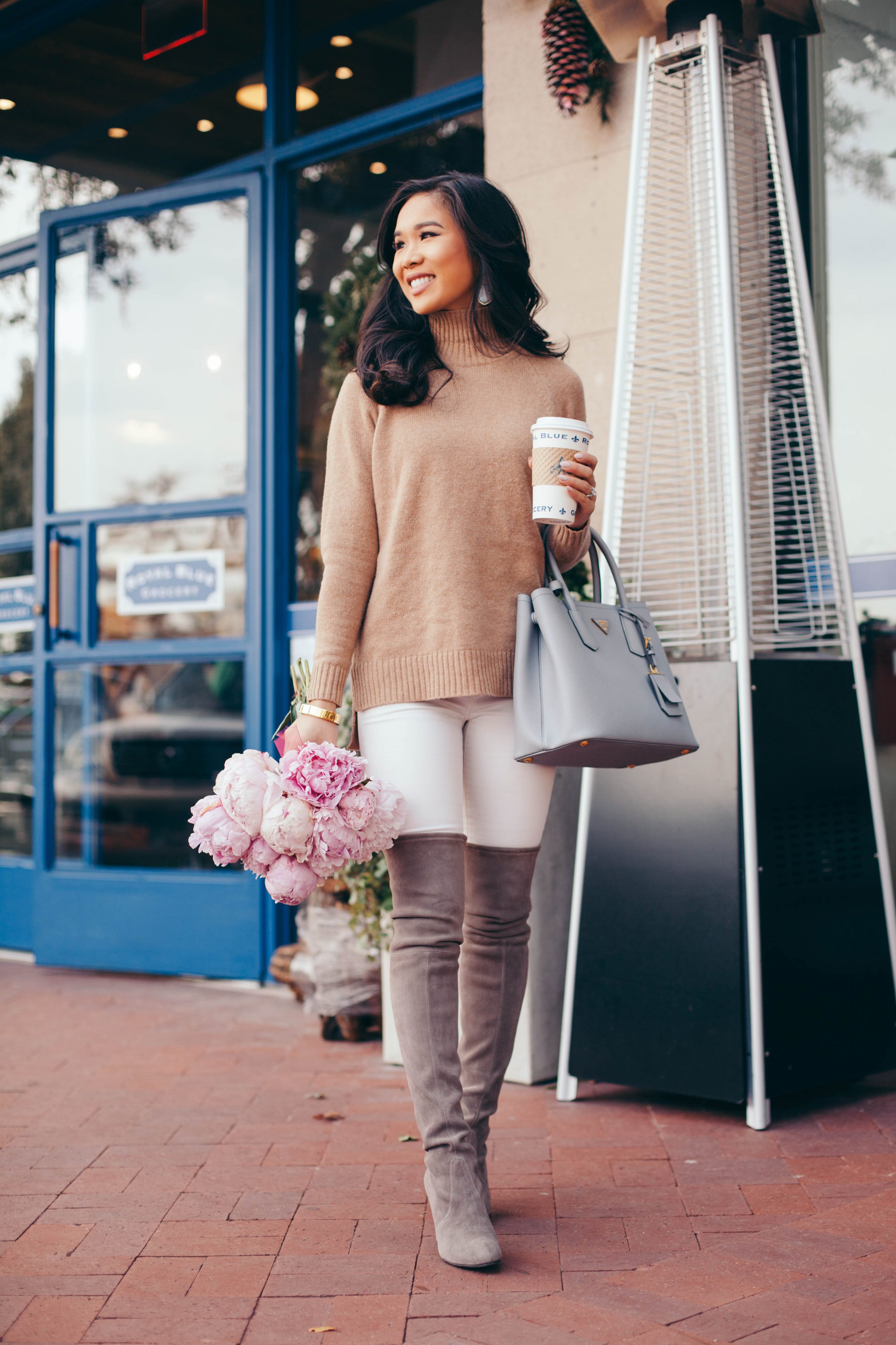 Blogger Hoang-Kim sips coffee at Royal Blue Grocery in Dallas wearing a soft sweater. over the knee boots and Prada Cuir handbag.