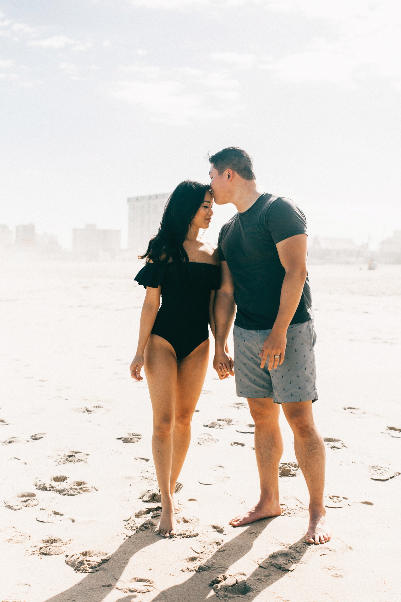 Beach engagement photos in a one piece off the shoulder swimsuit