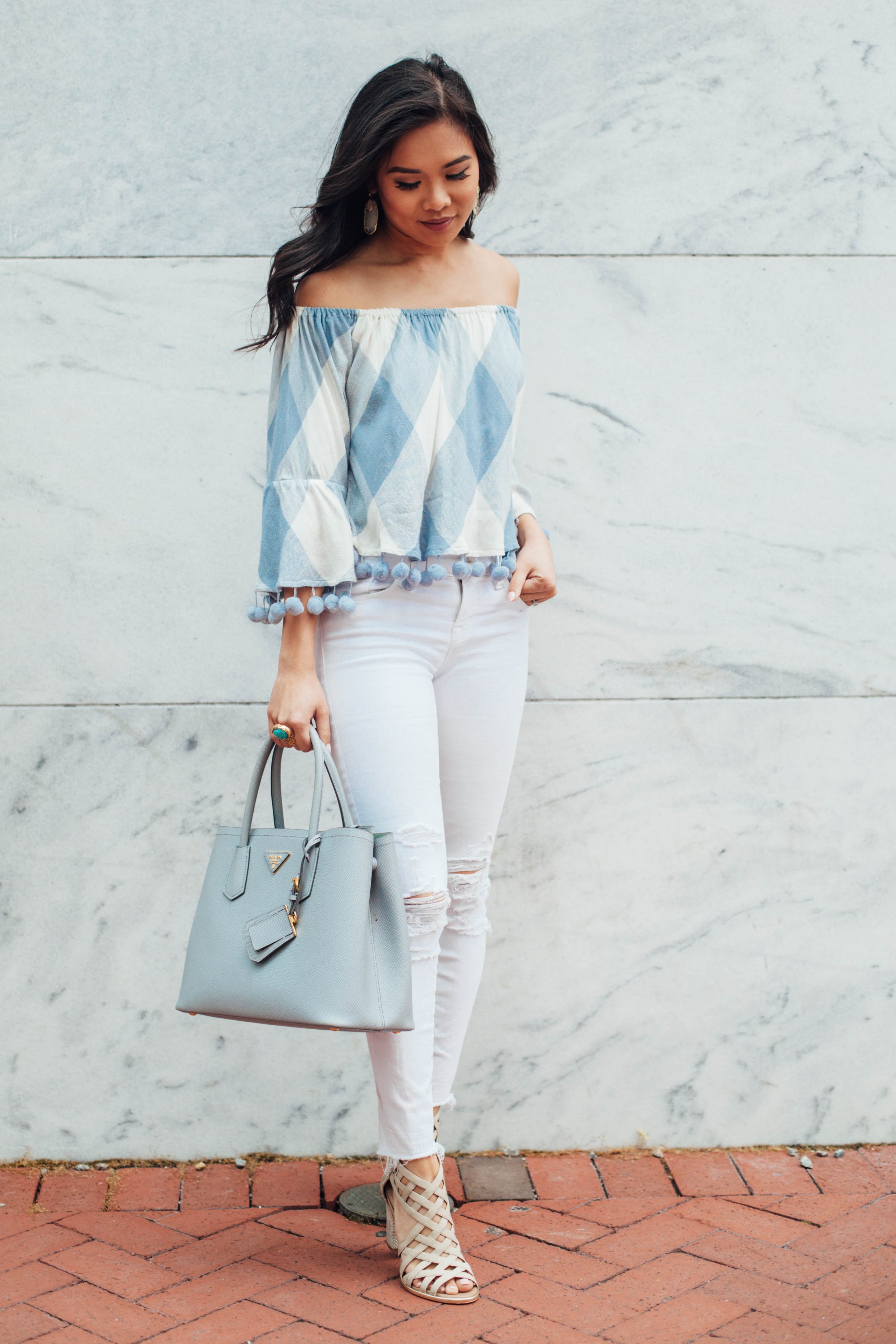 Off the shoulder top with pom pom trim and distressed jeans