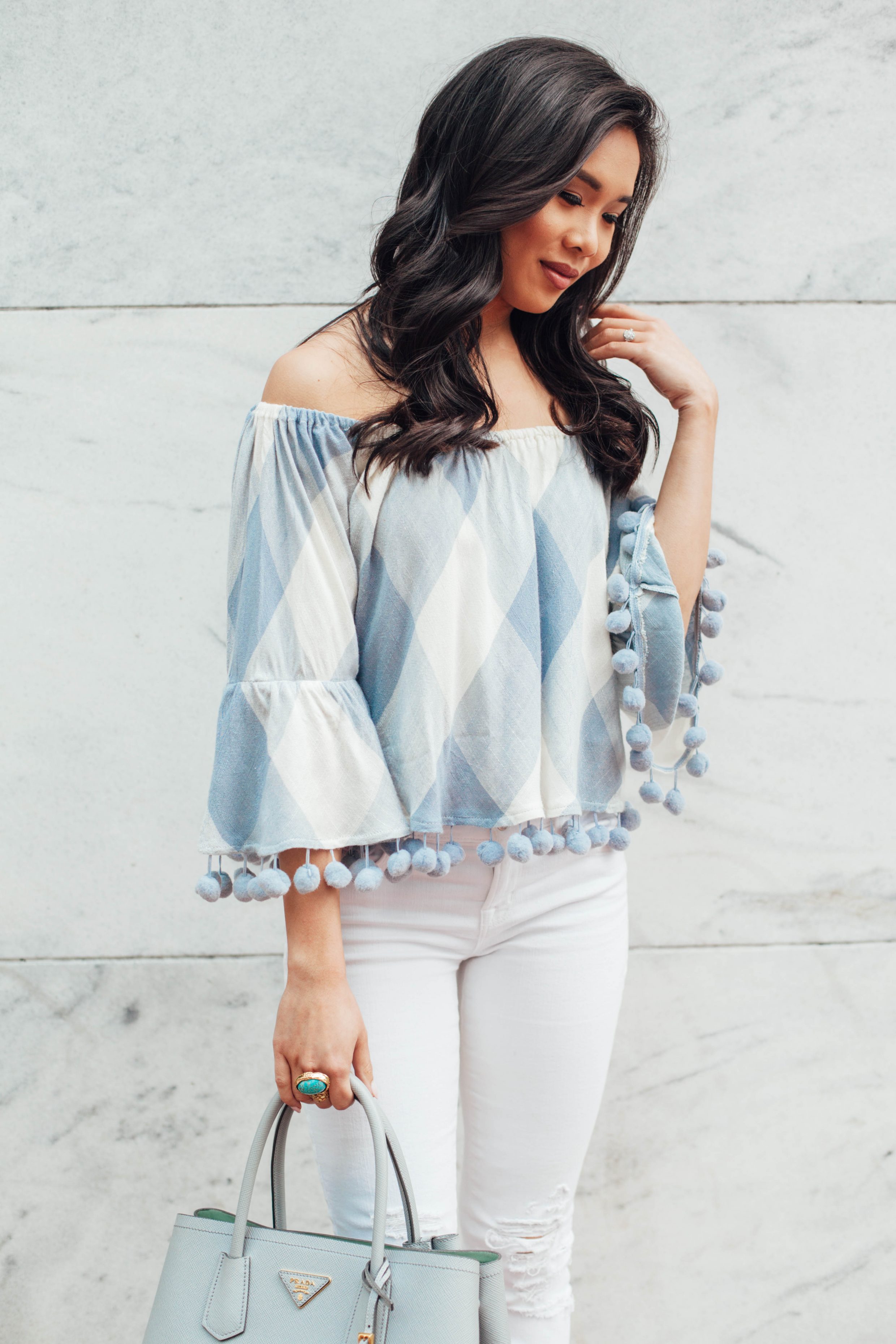 Off the shoulder top with pom pom trim and distressed jeans