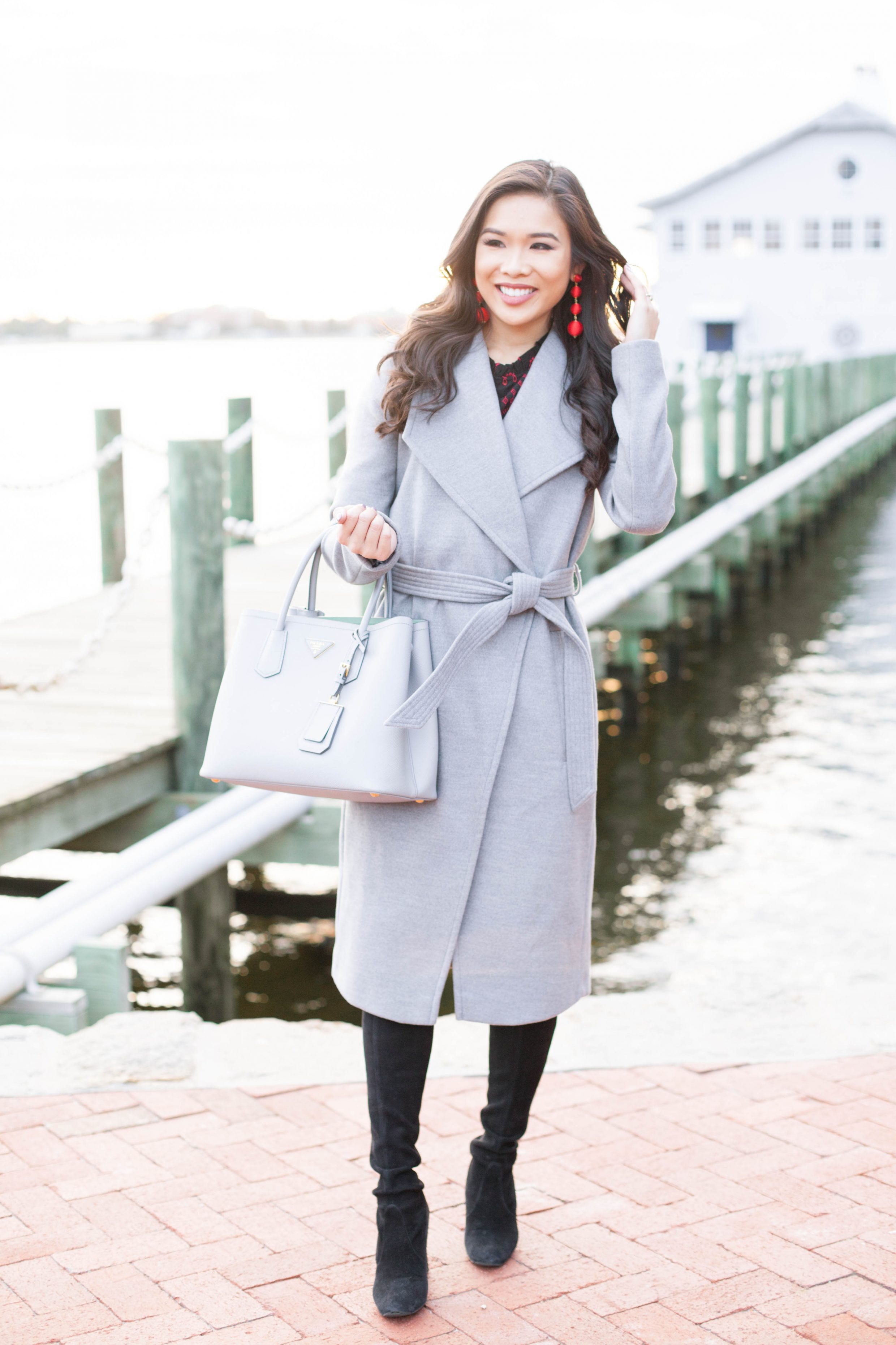 Gray belted coat with red drop earrings and over the knee boots