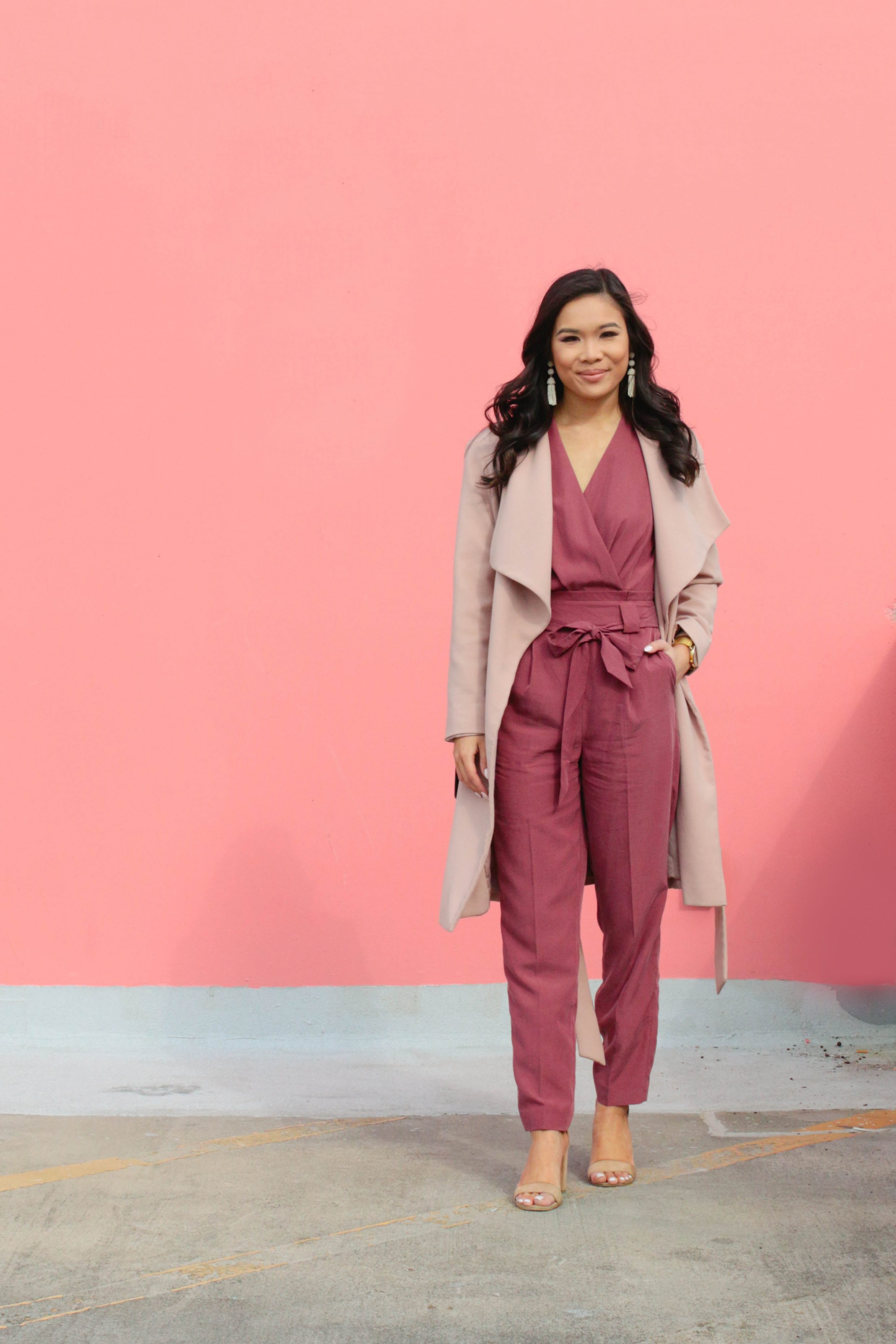 Mauve surplice jumpsuit with a blush wrap coat and tassel earrings for spring