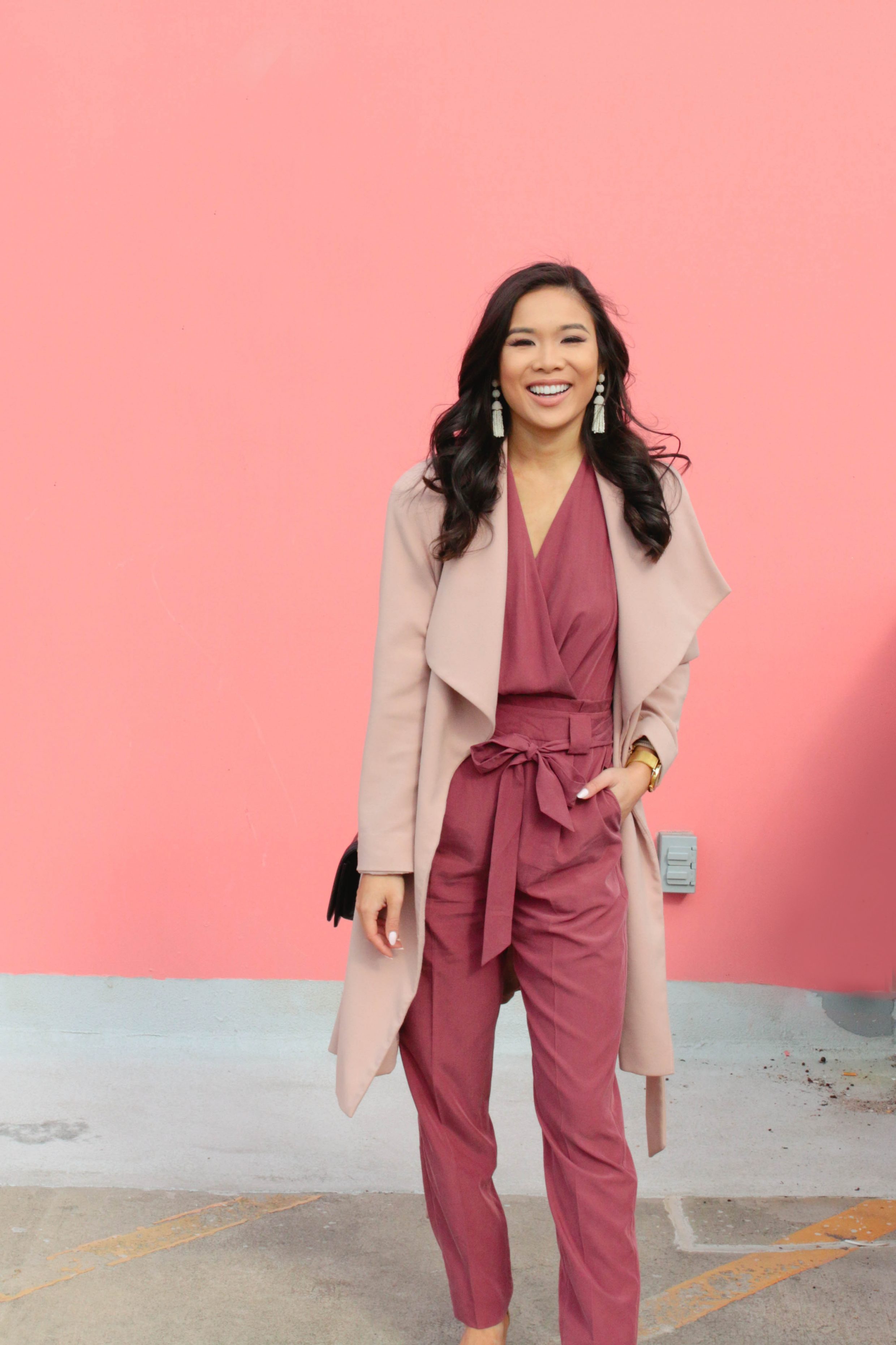 Mauve surplice jumpsuit with a blush wrap coat and tassel earrings for spring