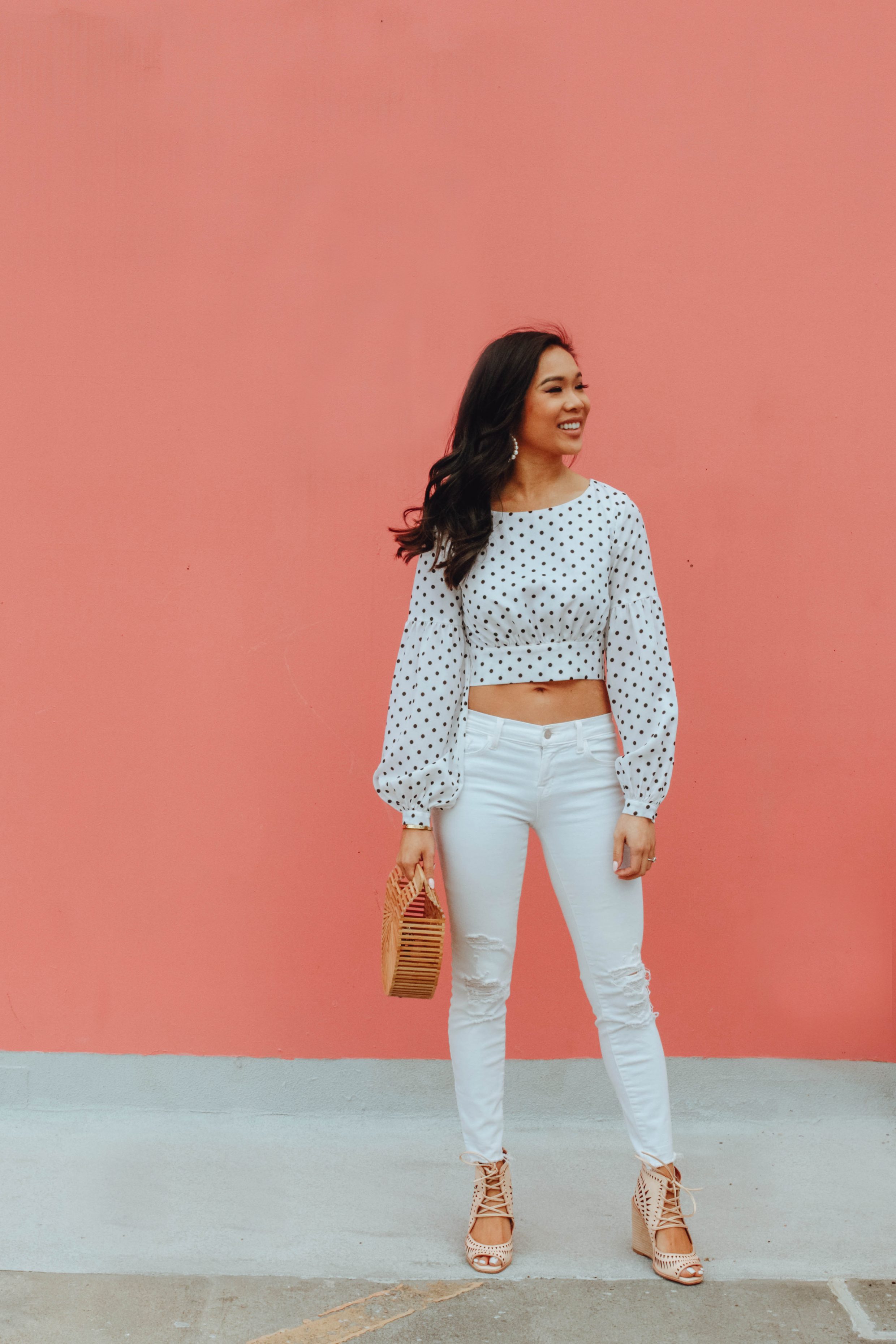 Hoang-Kim wears a polka dot crop top with white jeans and Cult Gaia bamboo bag