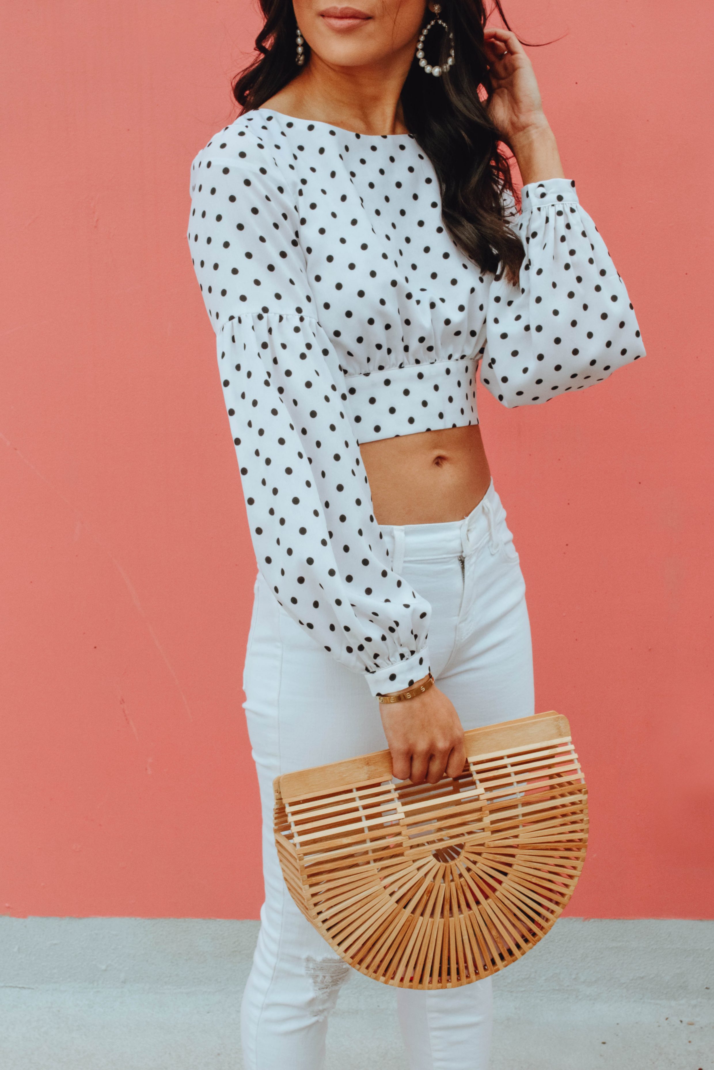 Hoang-Kim wears a polka dot crop top with white jeans and Cult Gaia bamboo bag