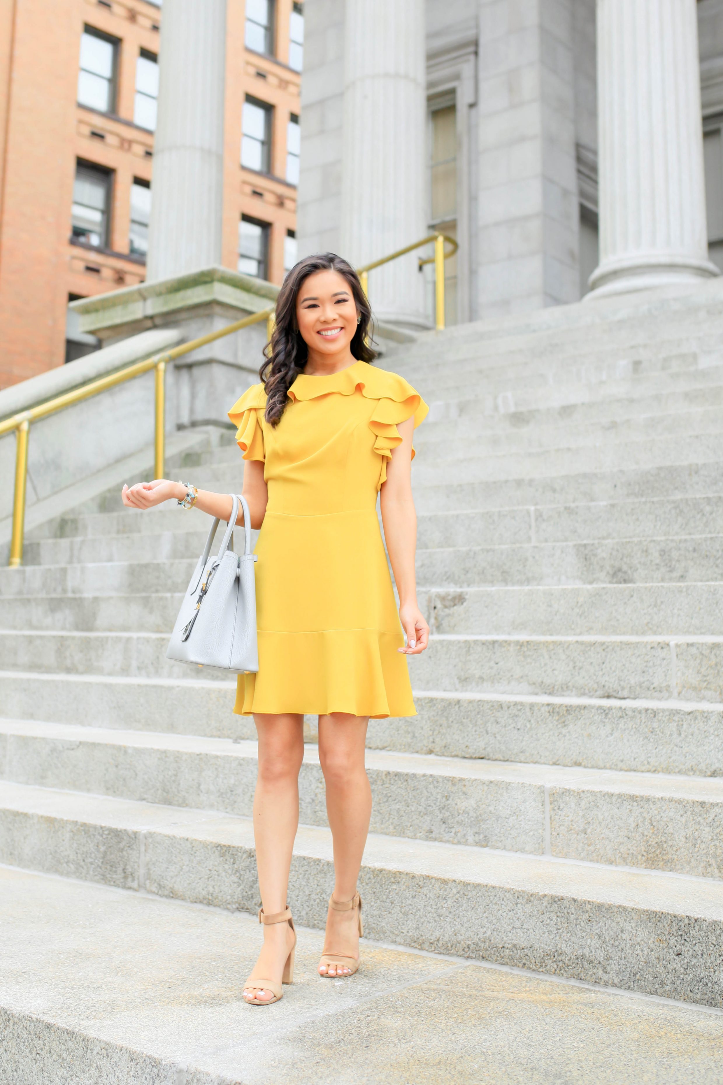 Hoang-Kim wears a marigold ruffle dress with suede block heels and Prada Cuir tote