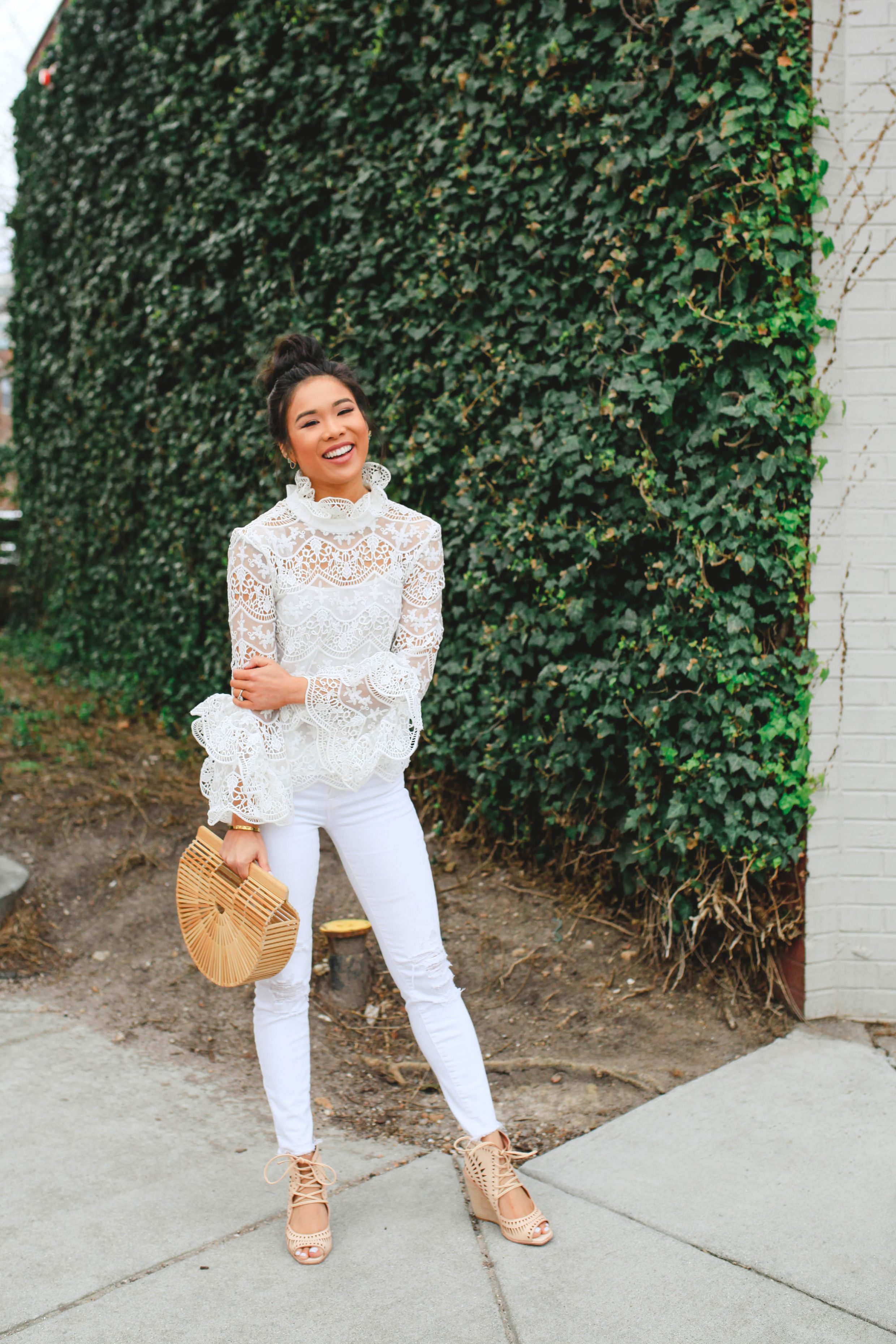 Hoang-Kim Cung wears a lace crochet top with white jeans and Cult Gaia Ark bag