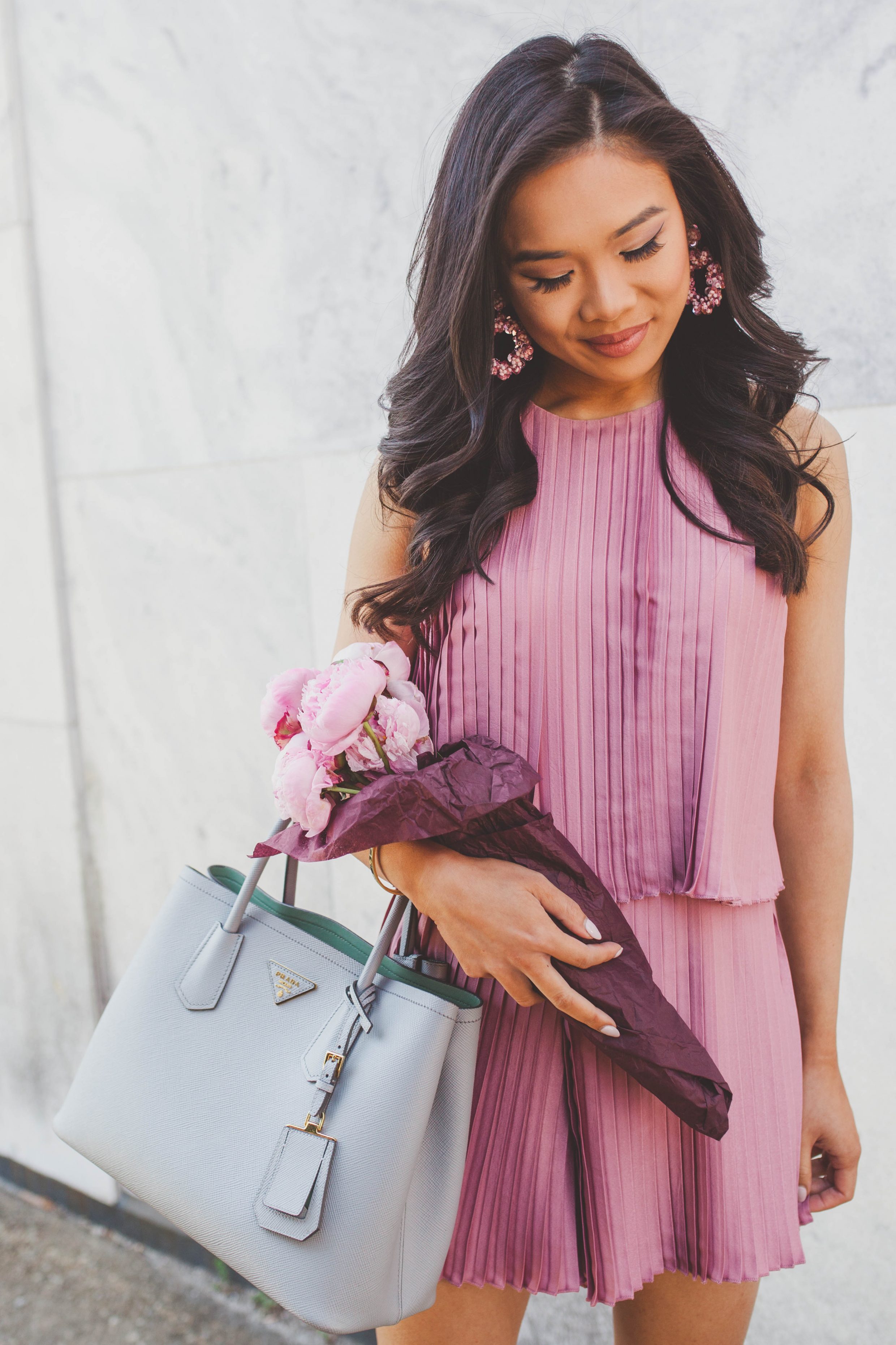 Blogger Hoang-Kim wears a pink pleated romper with pink sequin earrings and pink peonies