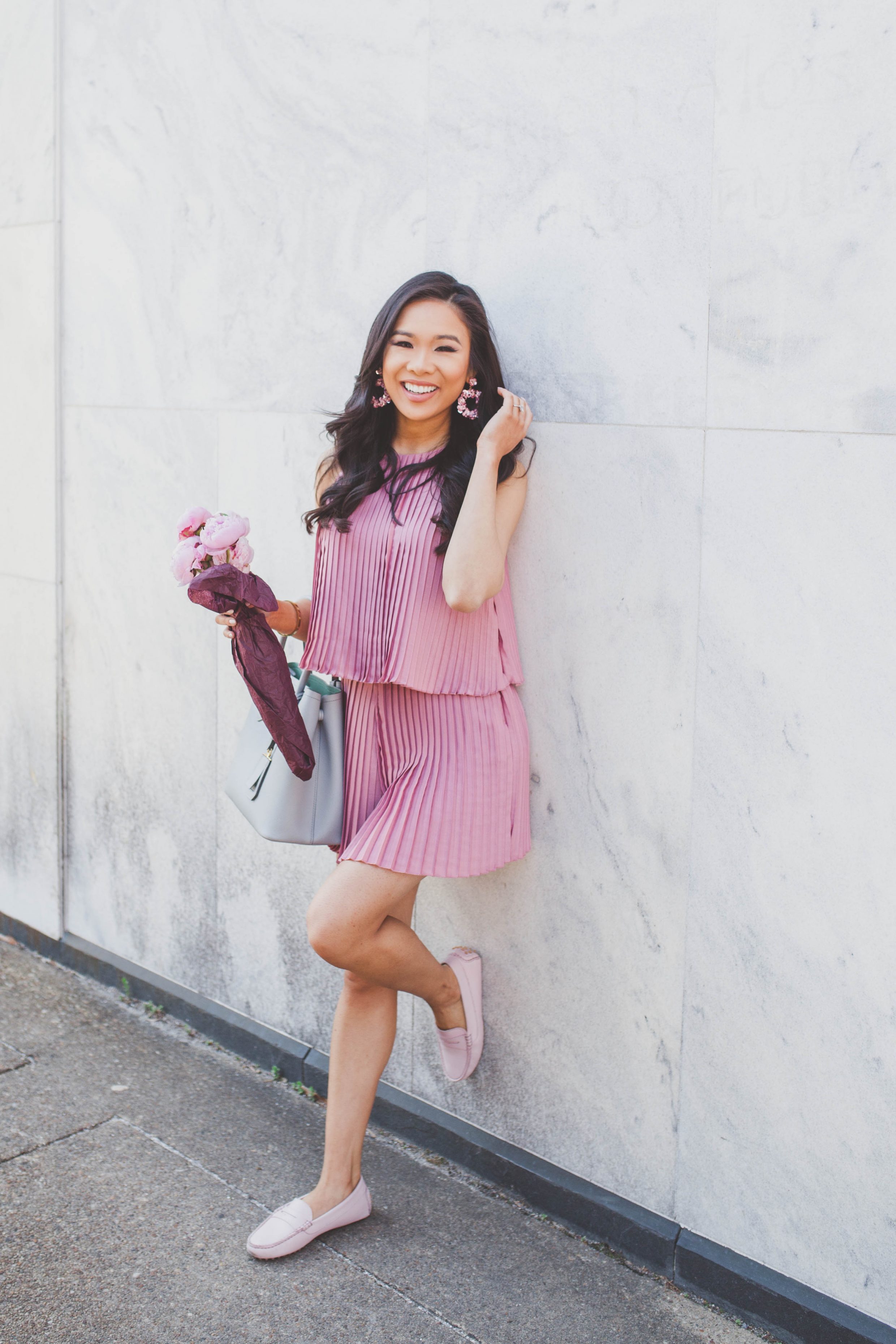 Blogger Hoang-Kim wears a pink pleated romper with blush penny drivers and pink peonies