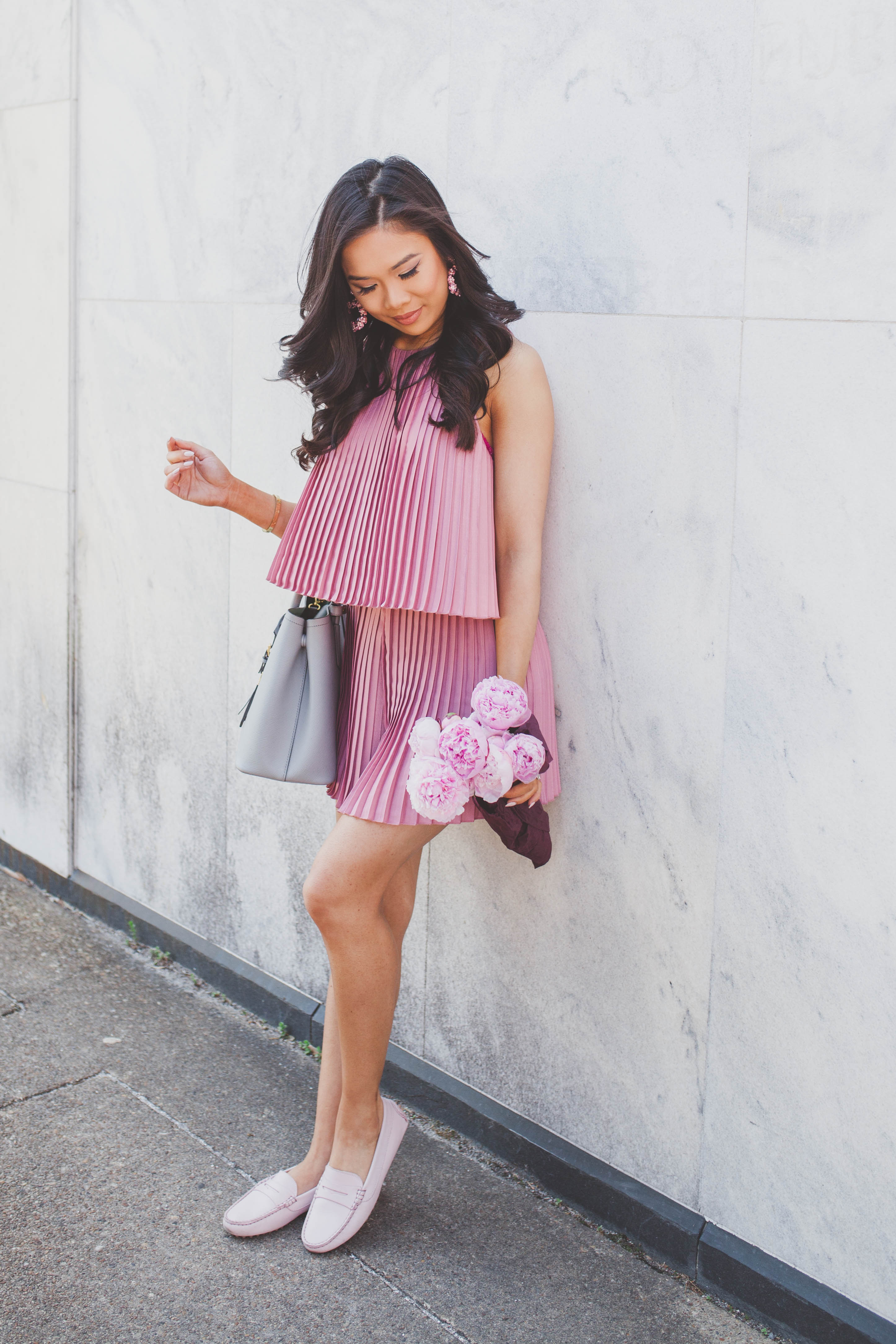 Blogger Hoang-Kim wears a pink pleated romper with blush penny drivers and pink peonies