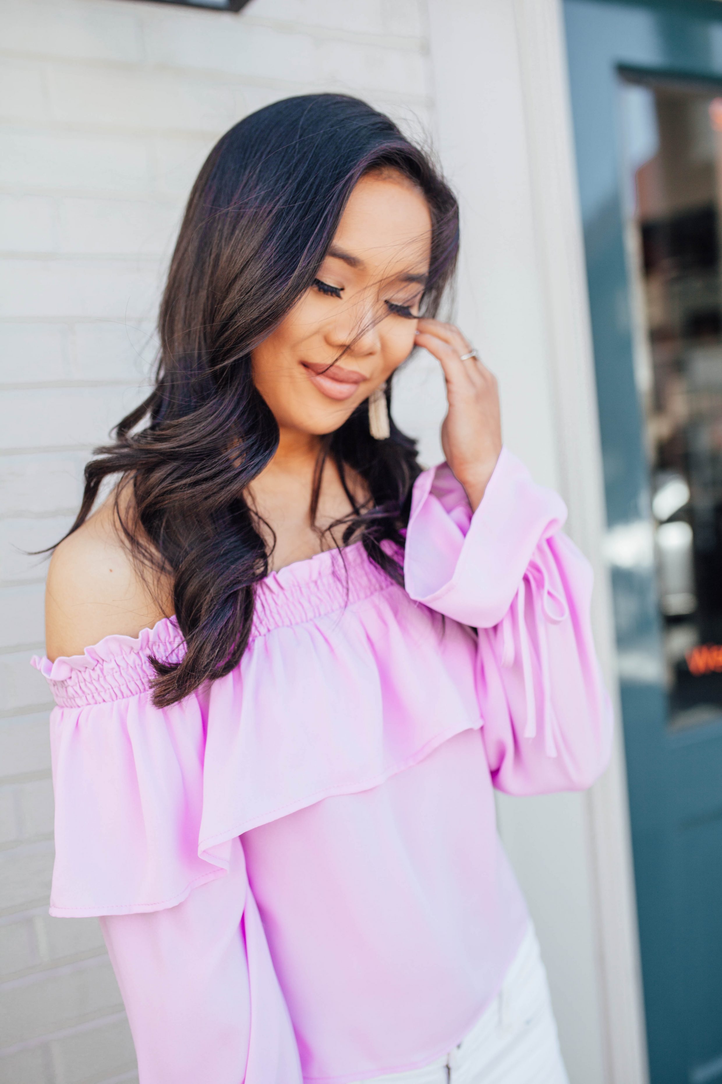 Hoang-Kim wears a lavender off-the-shoulder top with white tassel earrings