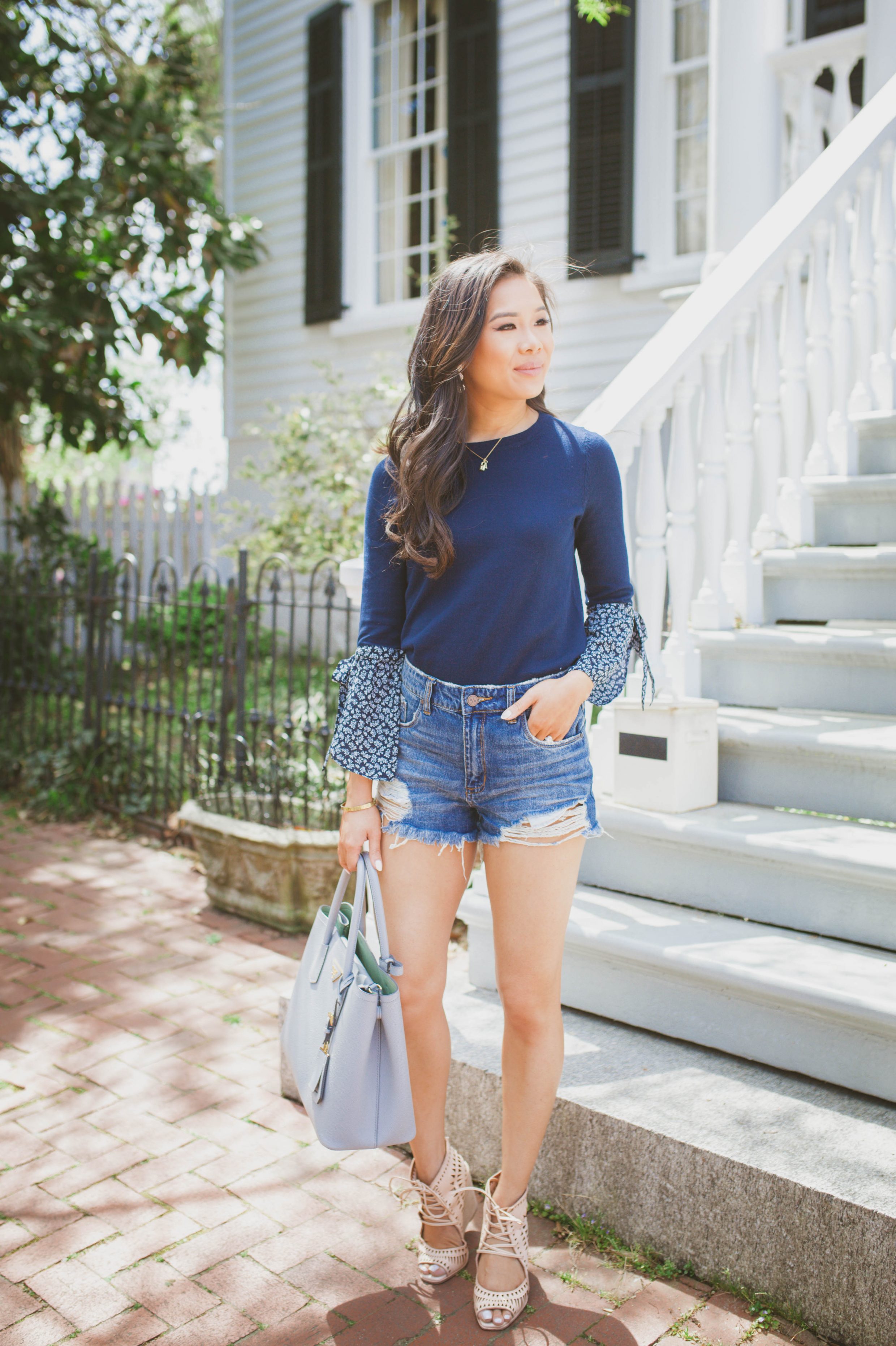 Hoang-Kim wears a navy floral tie-cuff sleeve top with distressed jeans for spring and Jeffrey Campbell wedges