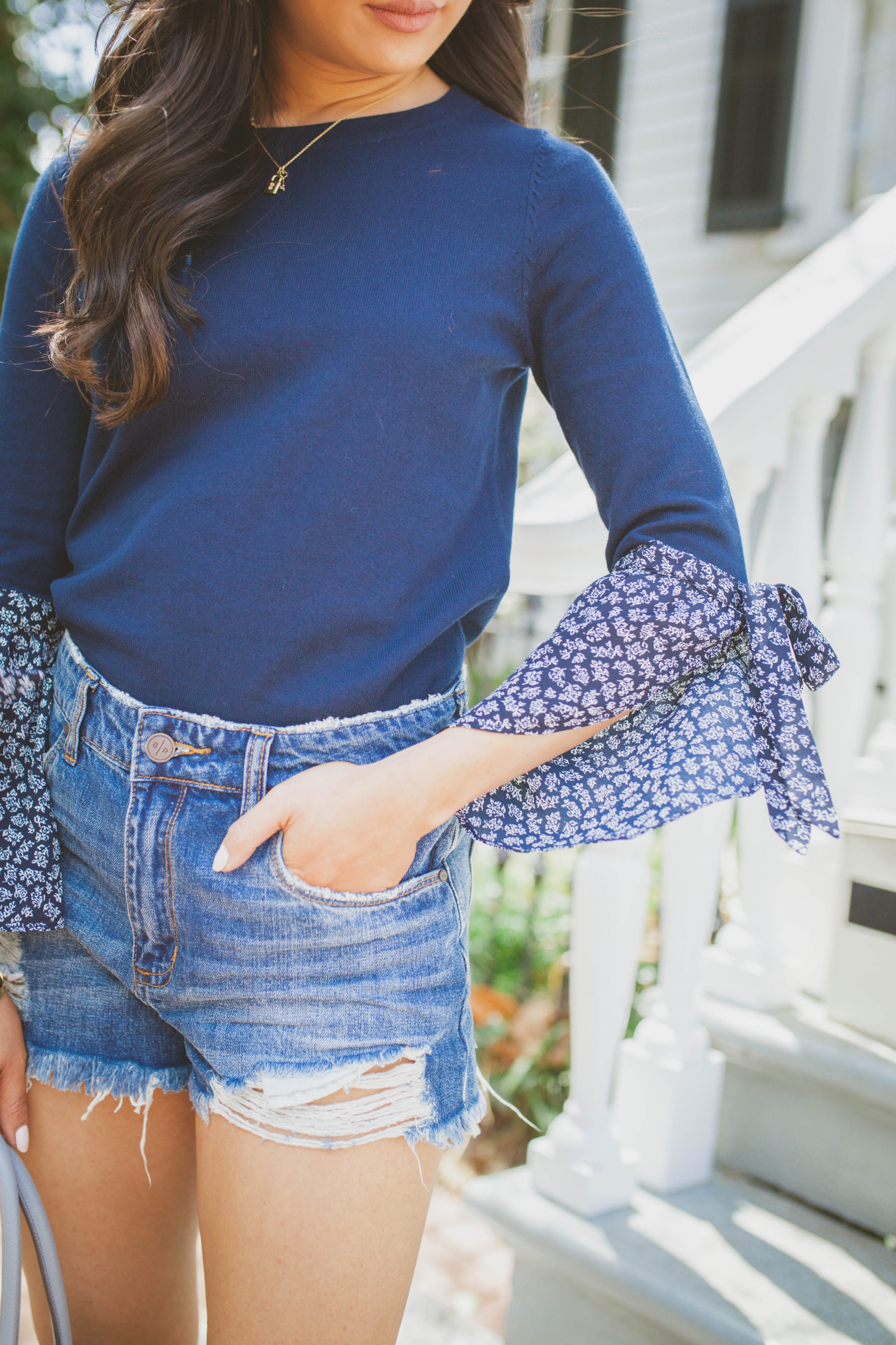 Hoang-Kim wears a navy floral tie-cuff sleeve top with distressed jeans for spring