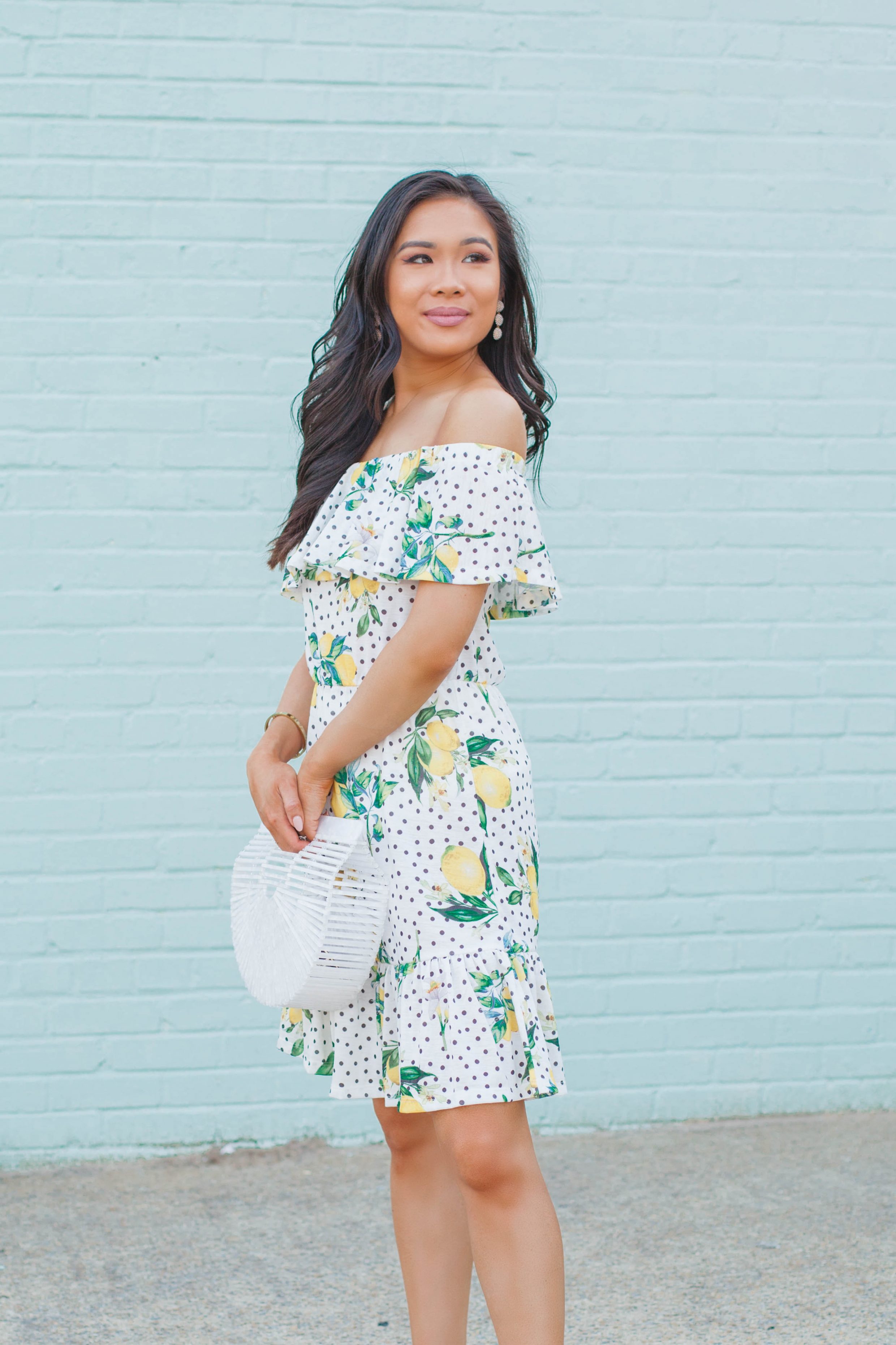 Off the shoulder lemon print dress with a white acrylic bag and Olive + Piper earrings for summer