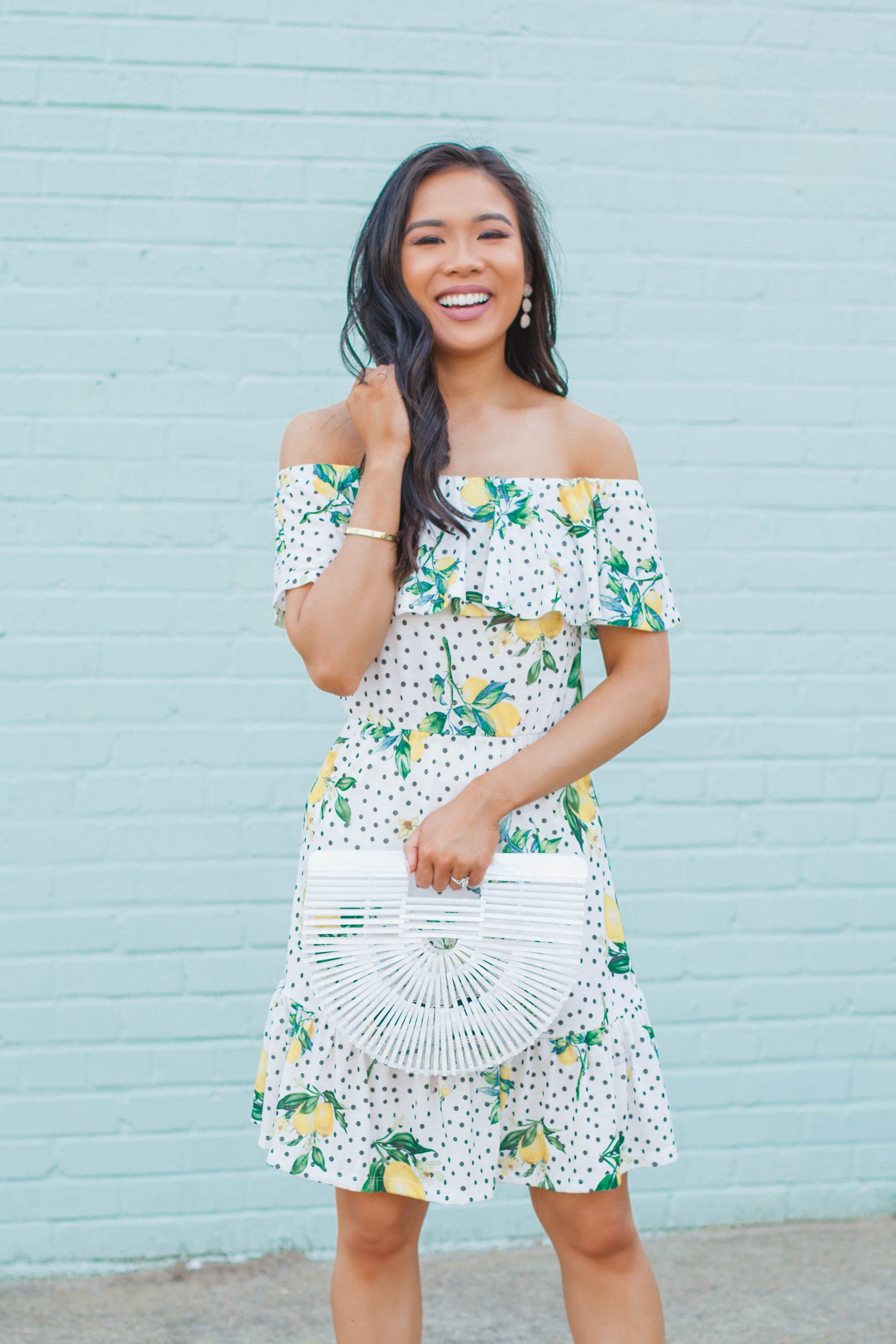 Off the shoulder lemon print dress with a white acrylic bag and Olive + Piper earrings for summer outfit idea