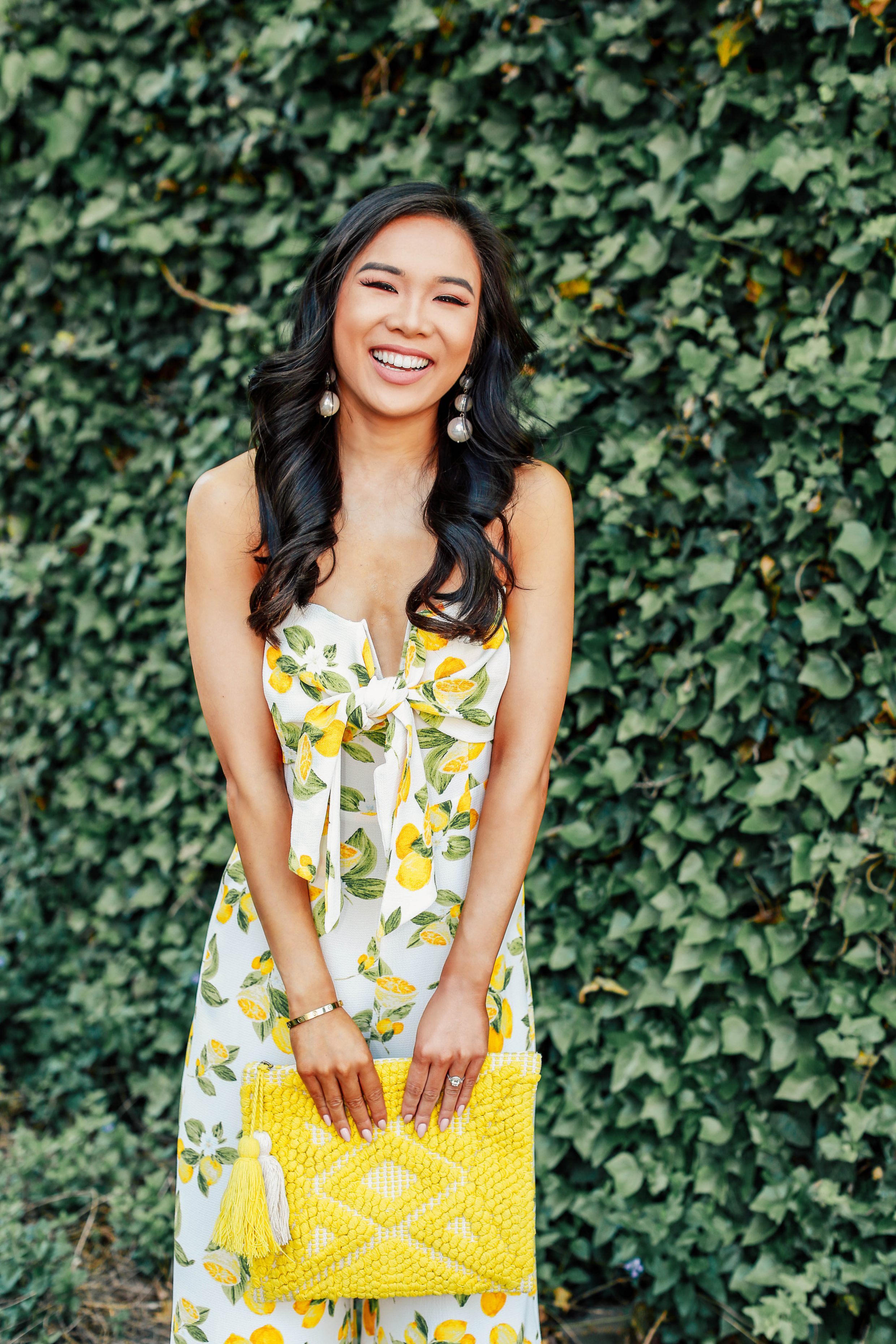 Hoang-Kim wears a lemon print jumpsuit, perfect for a summer outfit of the day with a Sole Society Palisades clutch