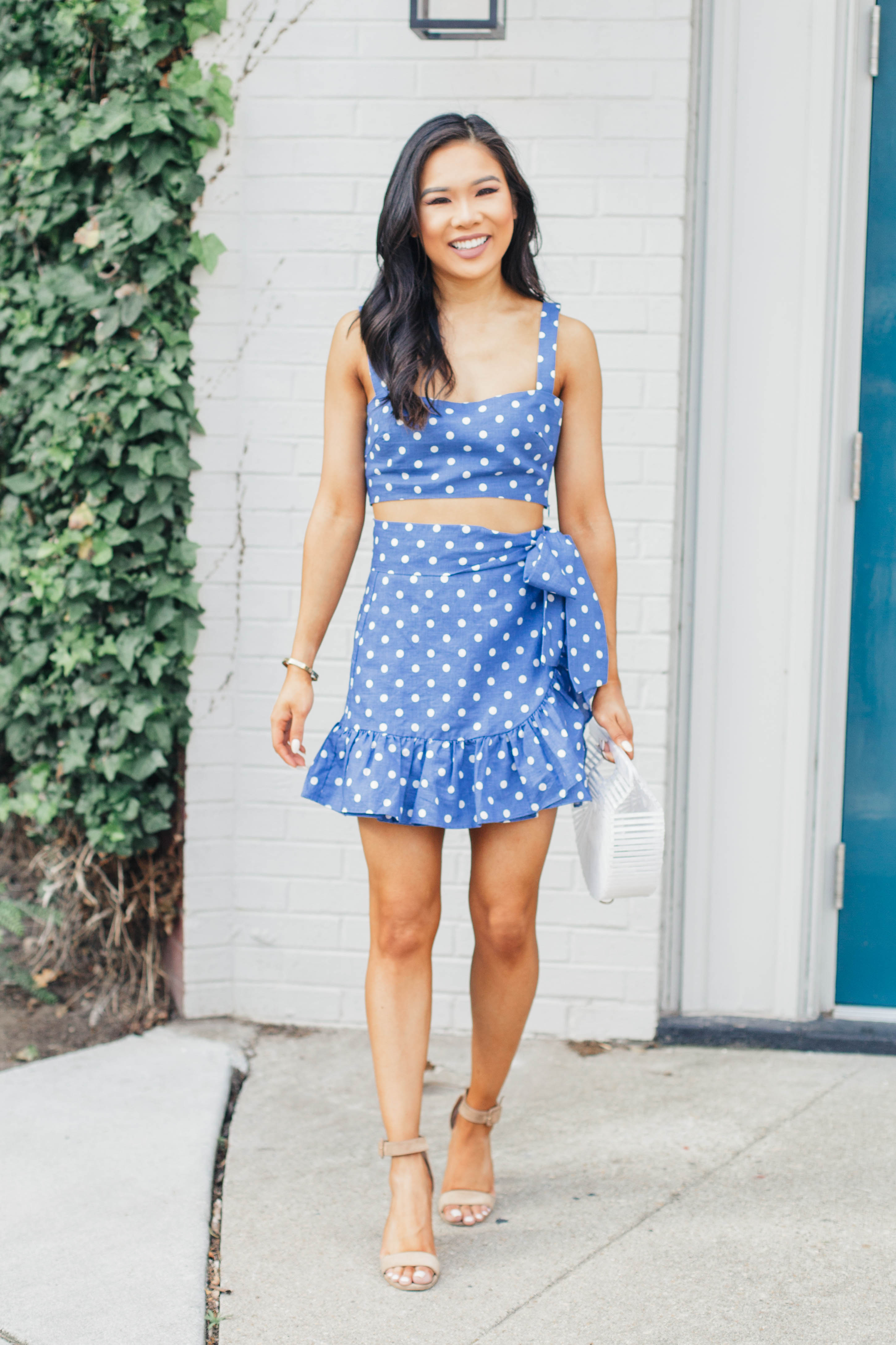 Sumer outfit idea: Blue polka-dot two piece set with white acrylic bag and suede sandals