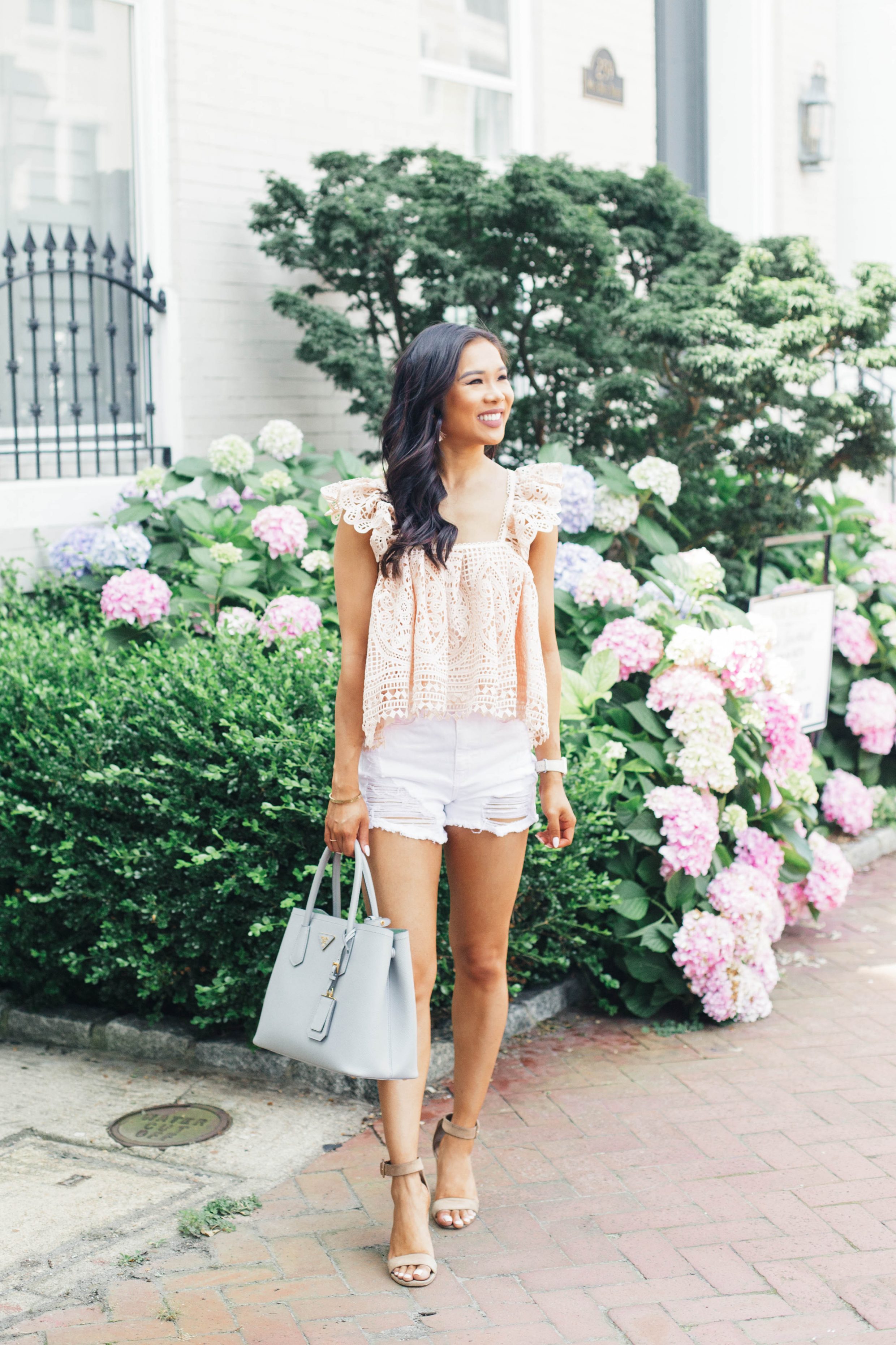Blogger Hoang-Kim wears a pink crochet cropped top and white distressed shorts for summer