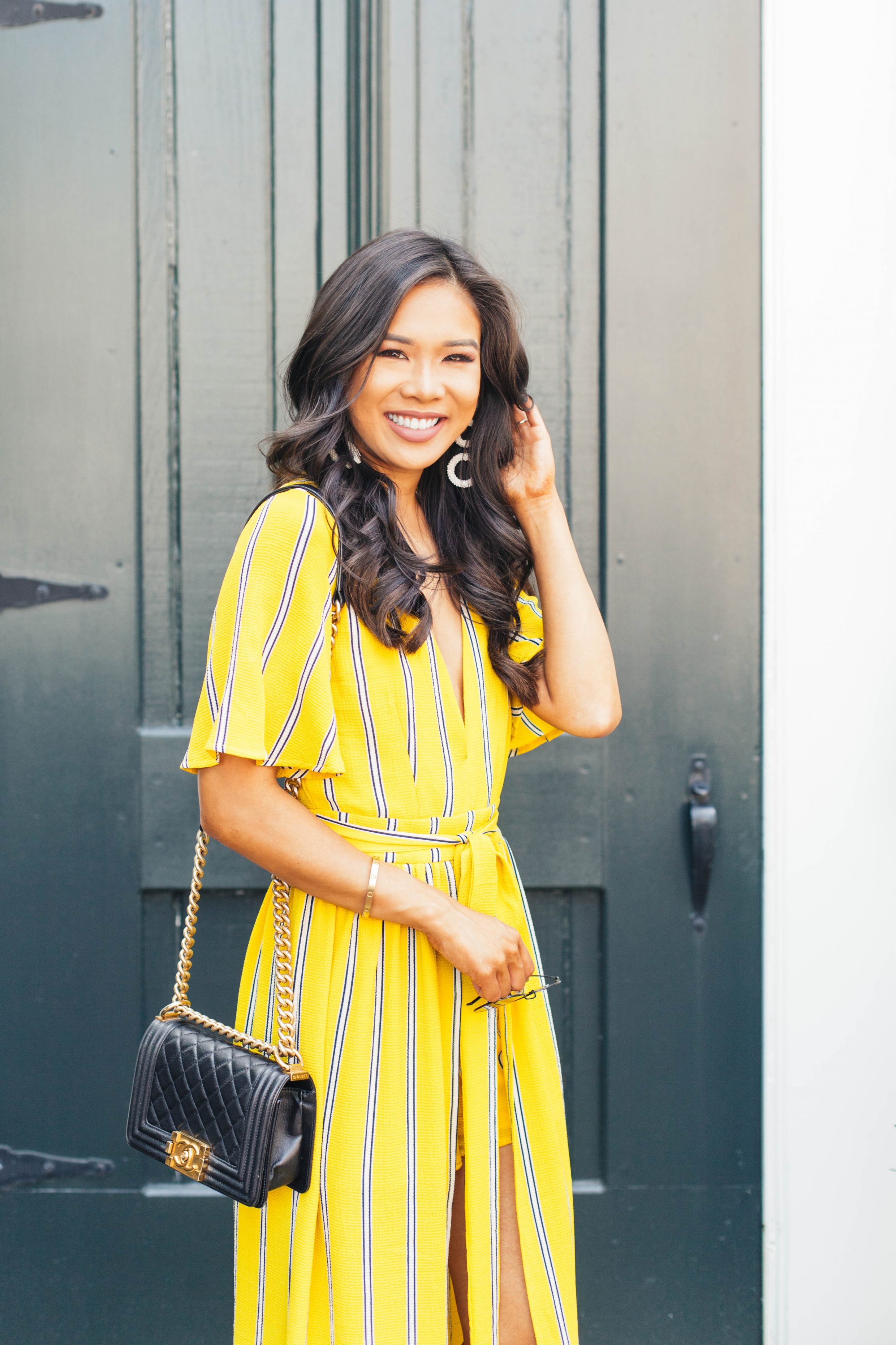 Hoang-Kim wears a yellow striped wrap jumpsuit for summer with a Chanel Boy bag