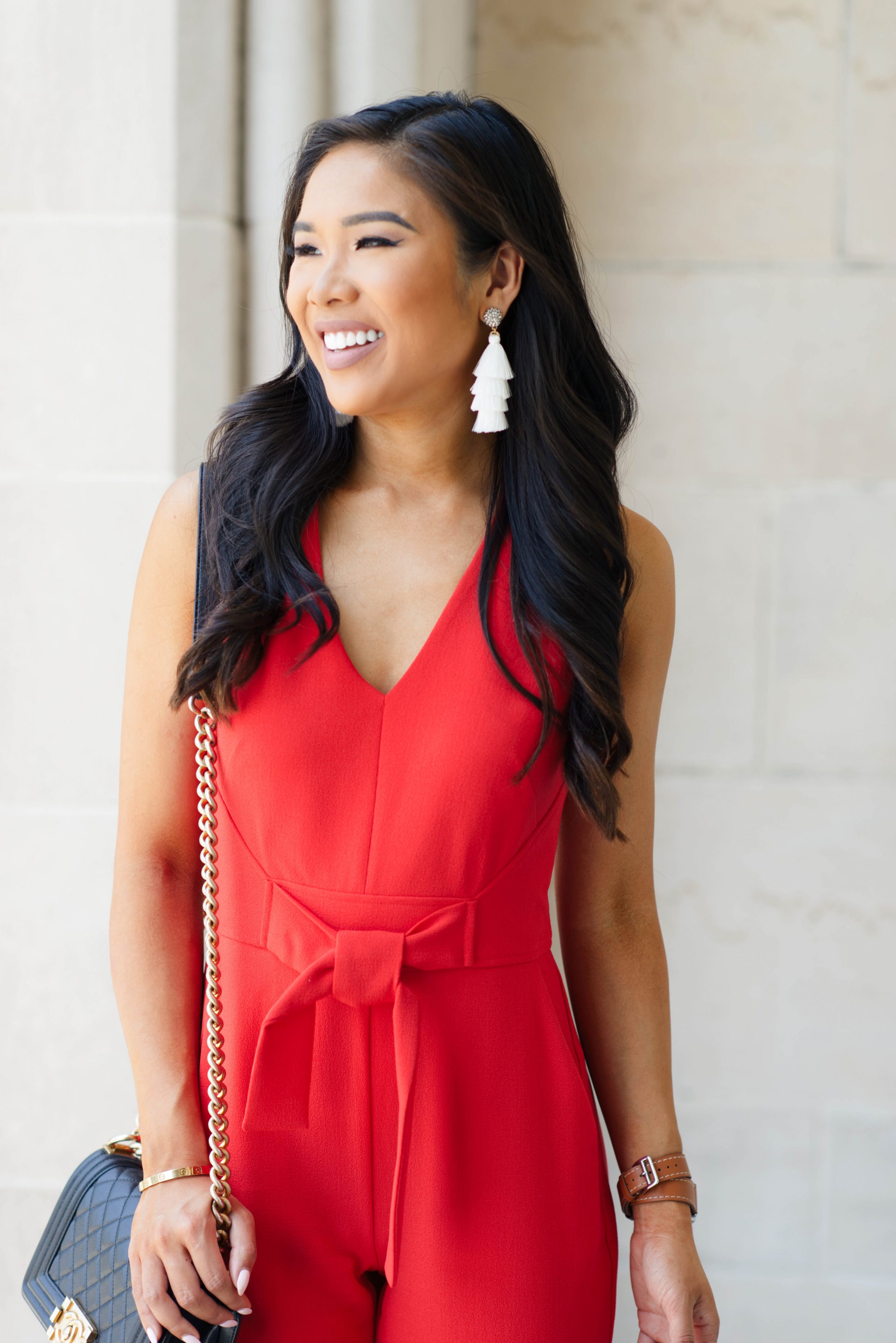 Blogger Hoang-Kim wears a red jumpsuit with pockets and Olive + Piper tassel earrings