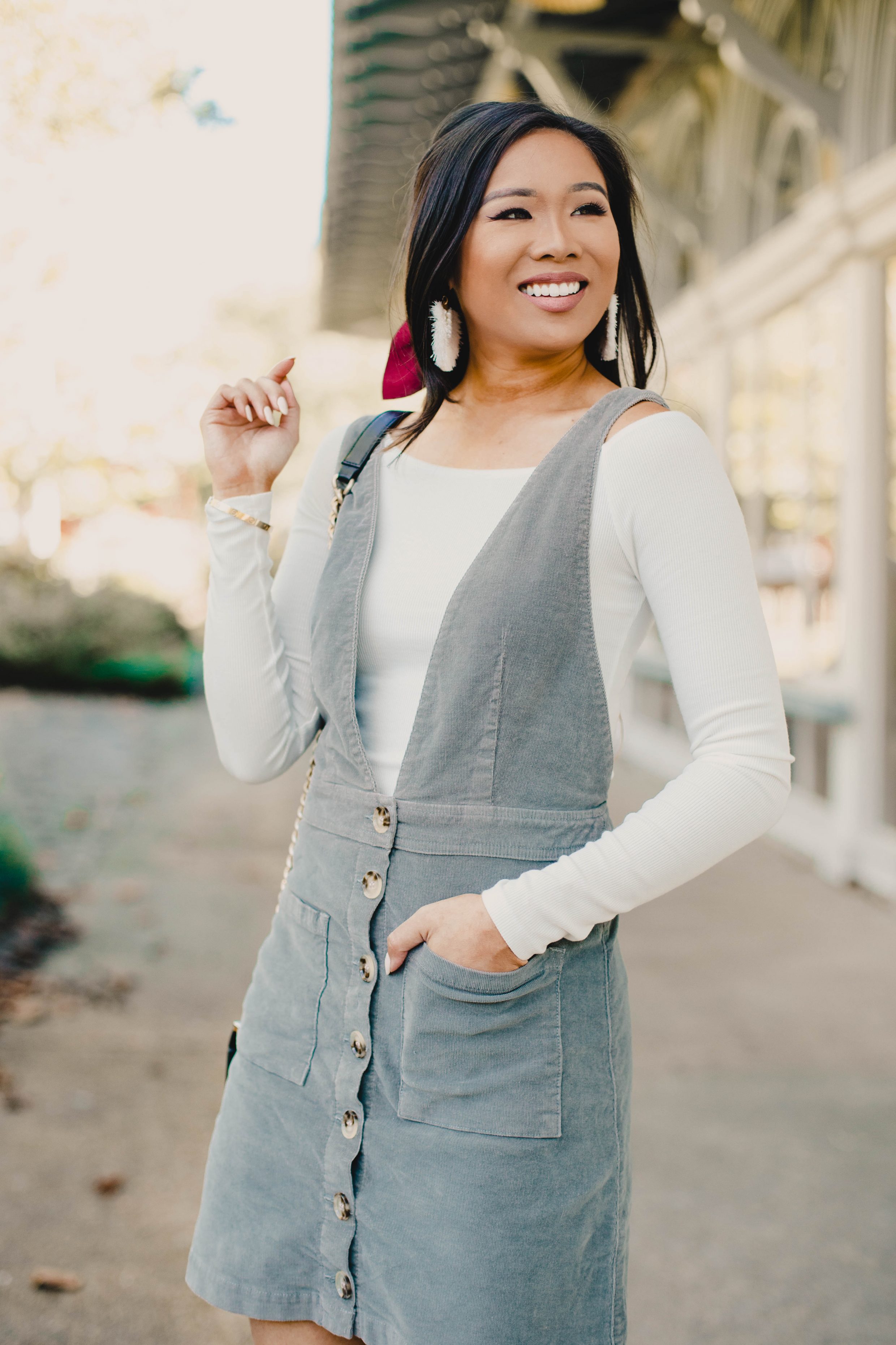 Blogger Hoang-Kim wears a Show Me Your Mumu corduroy overall dress with a white off-the-shoulder top for fall