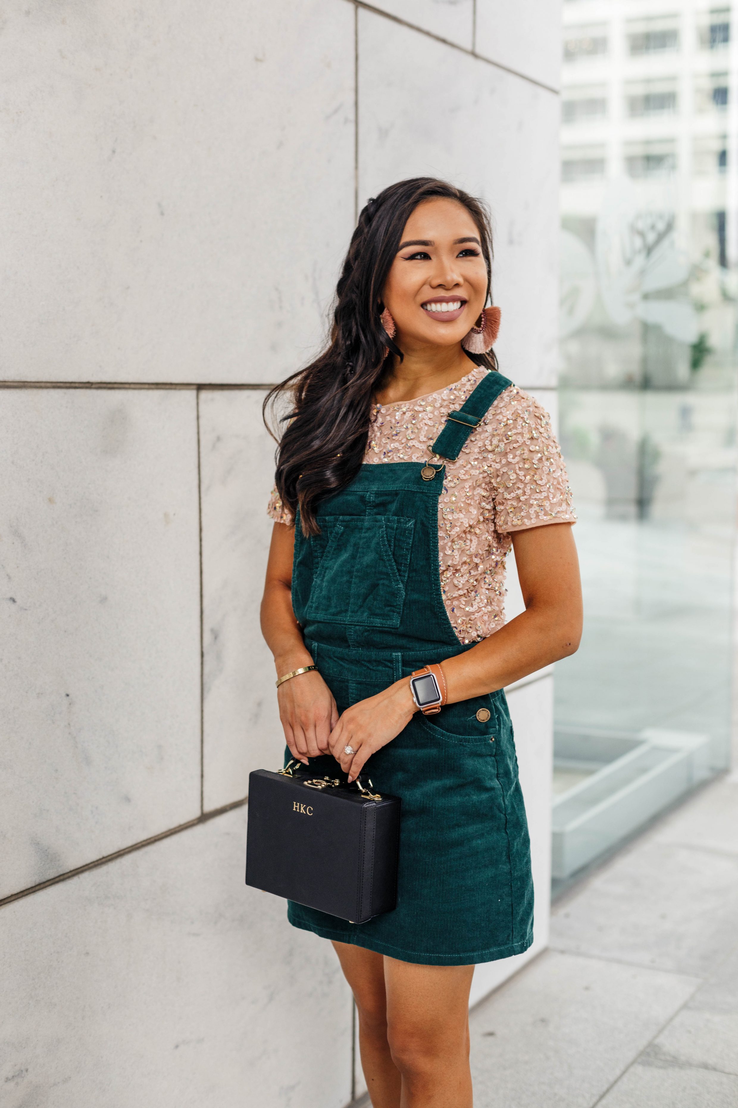 Hoang-Kim wears a green corduroy overall dress with a blush sequin t-shirt