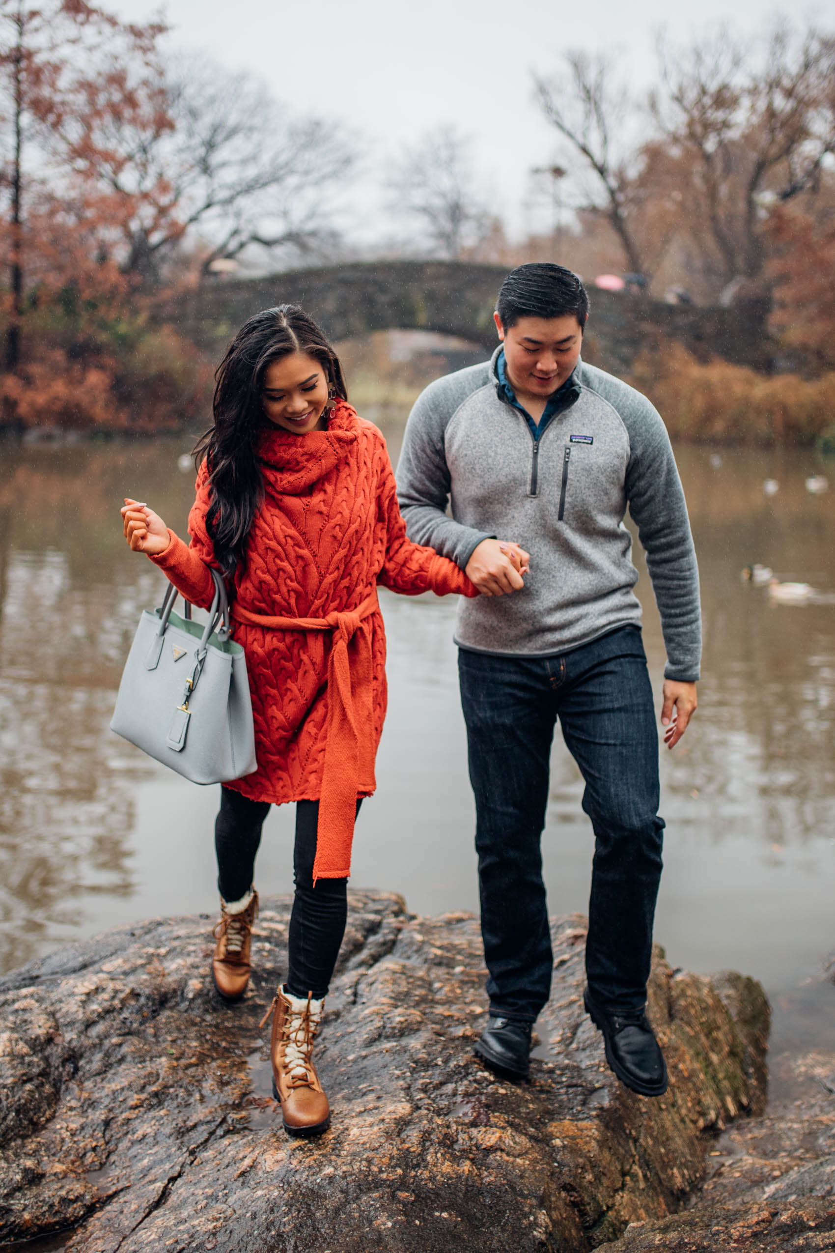 Blogger Hoang-Kim wears a red sweater dress with warm leggings and boots at Central Park during winter. Jonathan wears a Patagonia Better Sweater