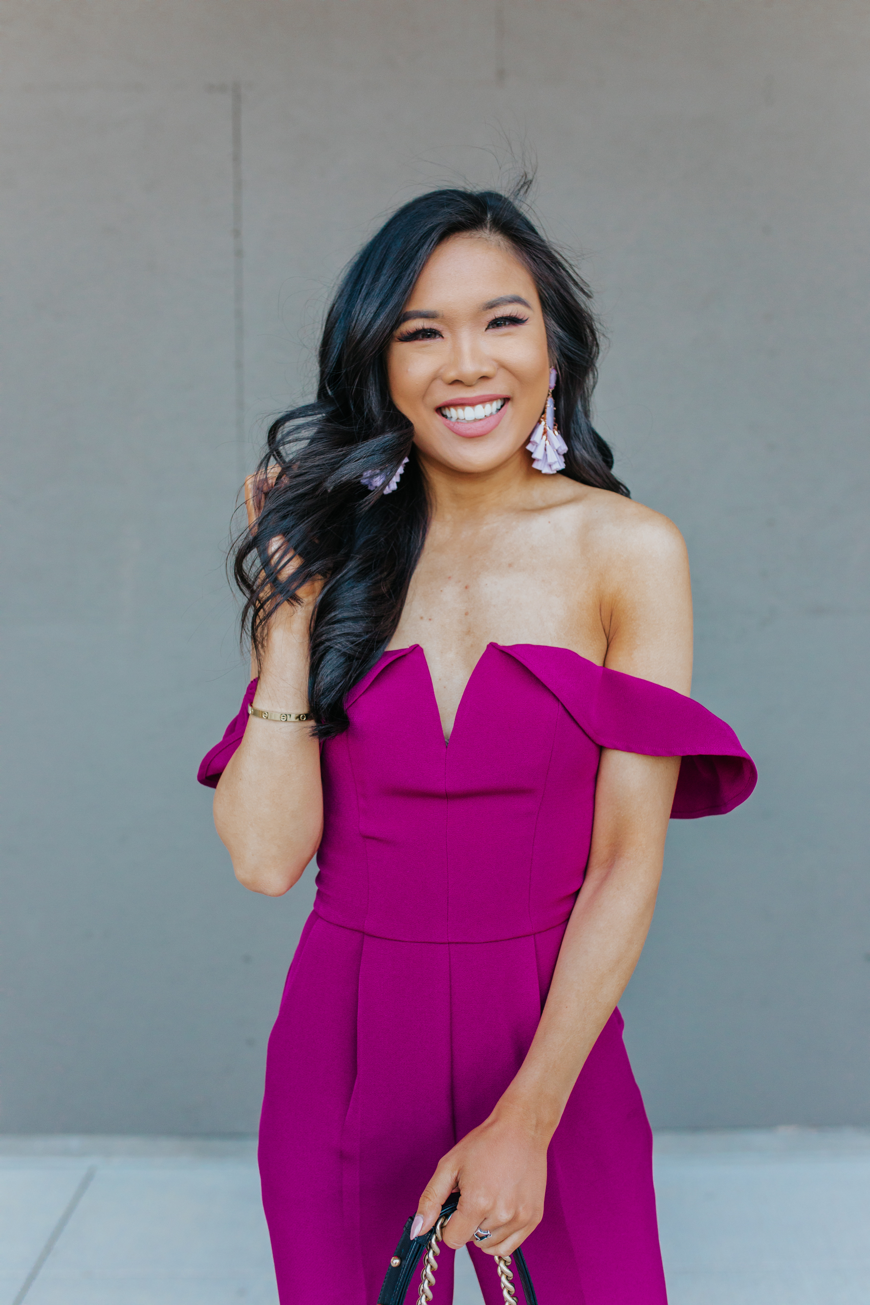 Asian woman wears a magenta off-the-shoulder jumpsuit
