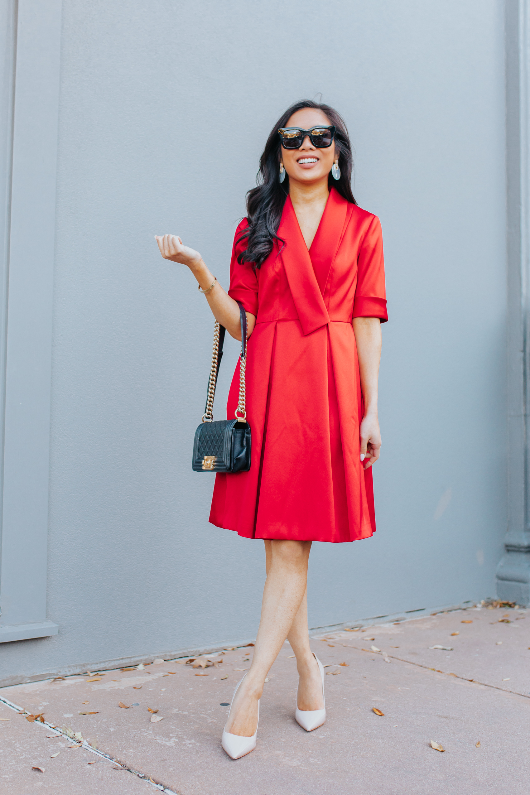 Asian woman wears a satin red dress with an oversized lapel and Celine earrings
