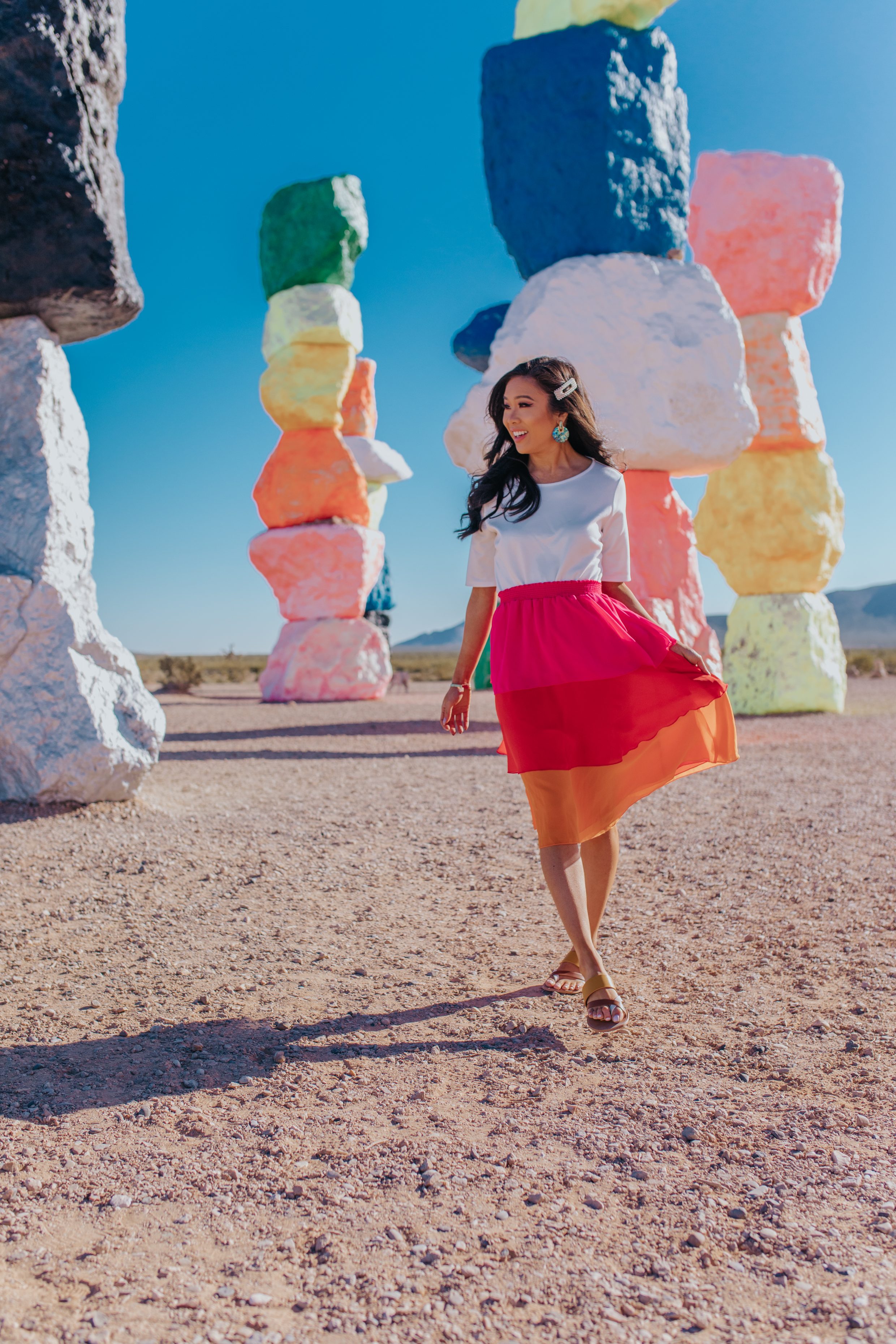 Hoang-Kim wears a white tee, colorful skirt and Dolce Vita Sandals at Seven Magic Mountains
