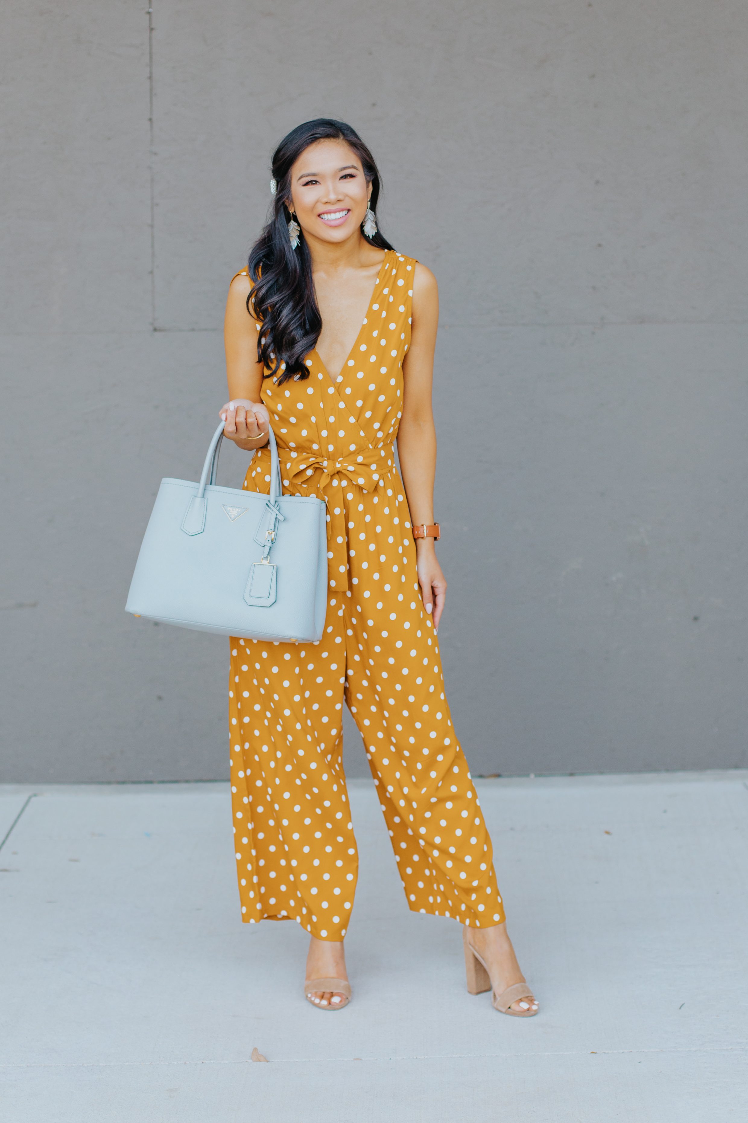 Blogger Hoang-Kim wears a gold polka dot jumpsuit with Kendra Scott earrings