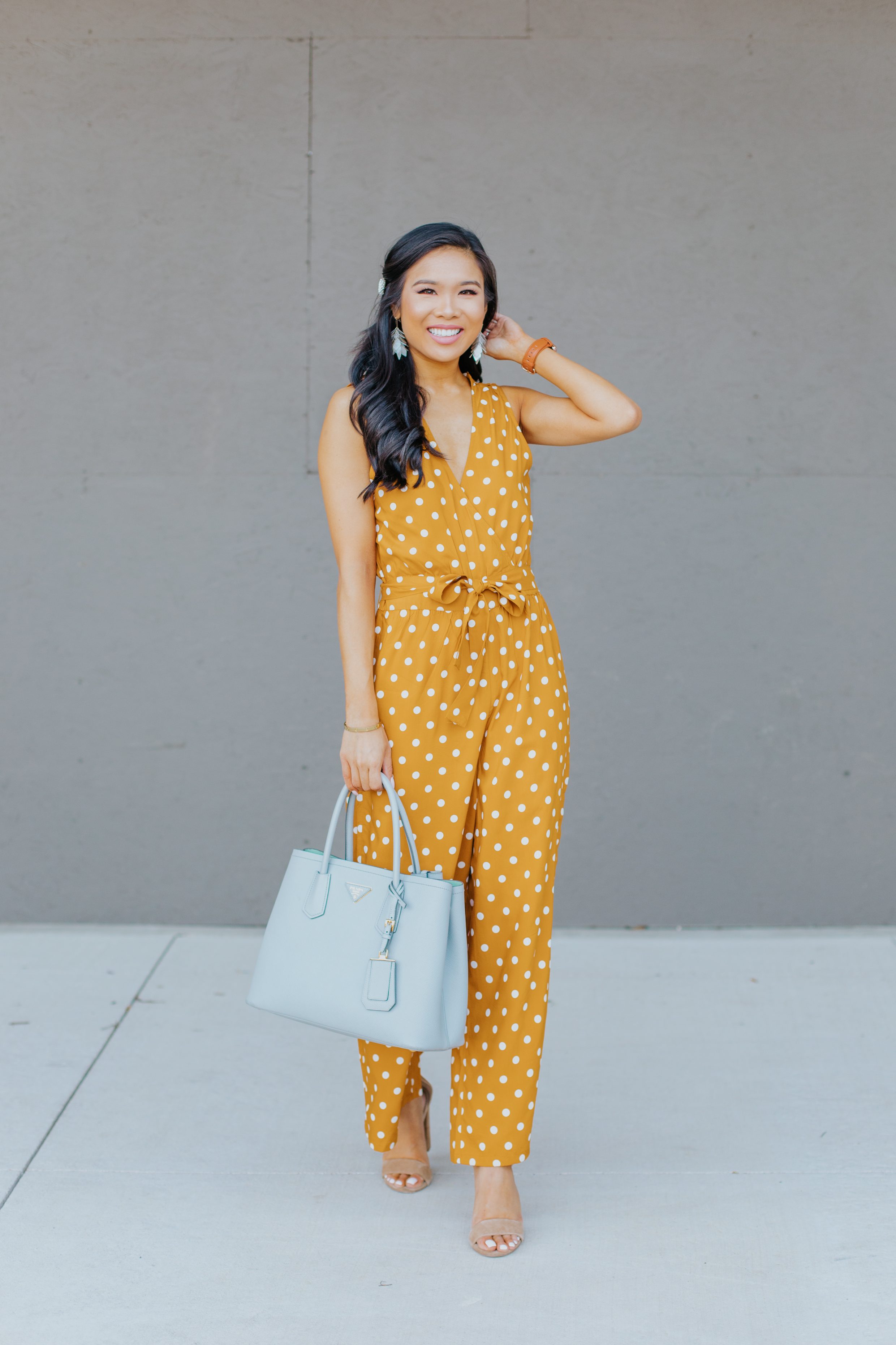 Petite brunette woman wears a polka dot jumpsuit