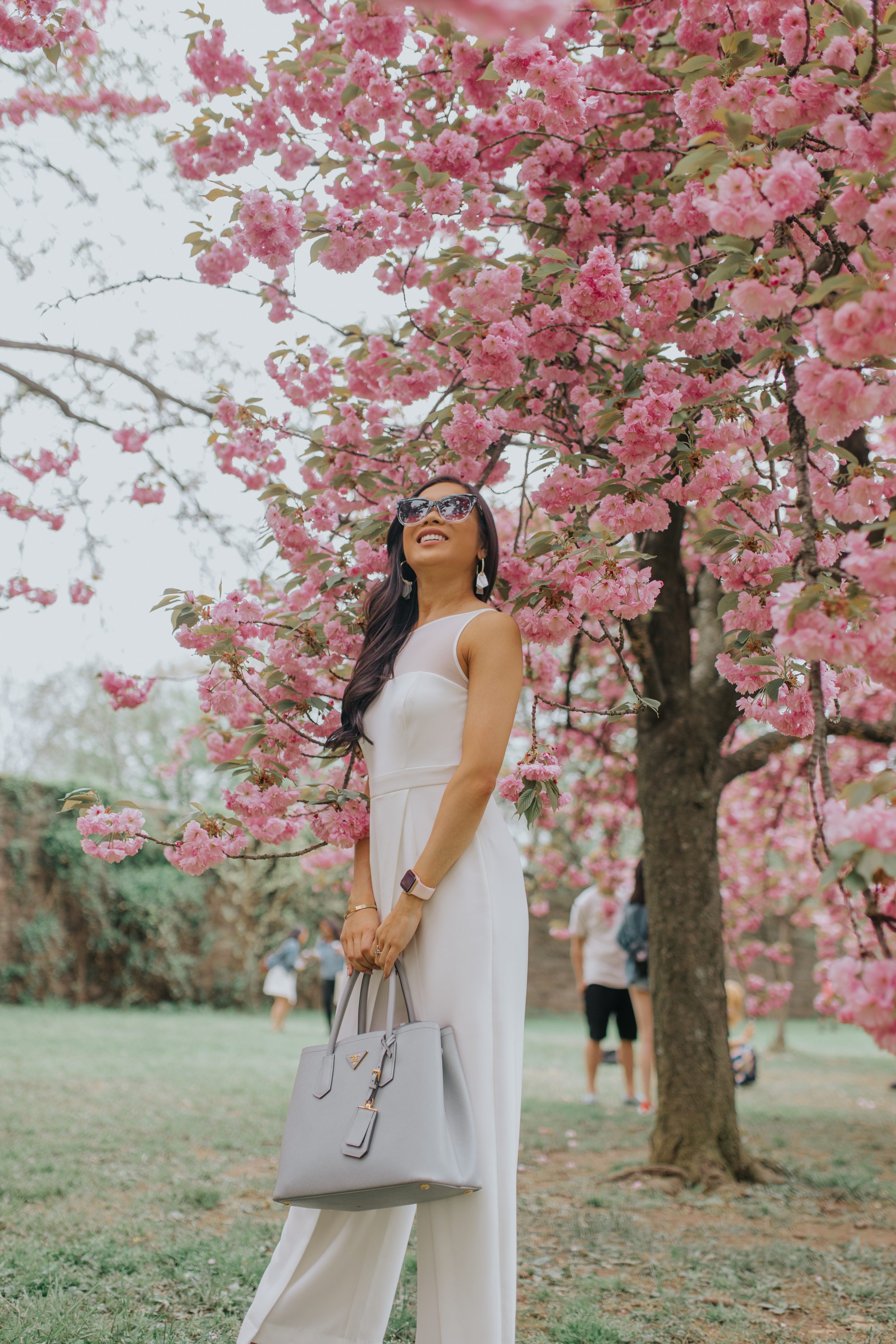 Asian woman wears a white jumpsuit to see D.C. Cherry blossoms