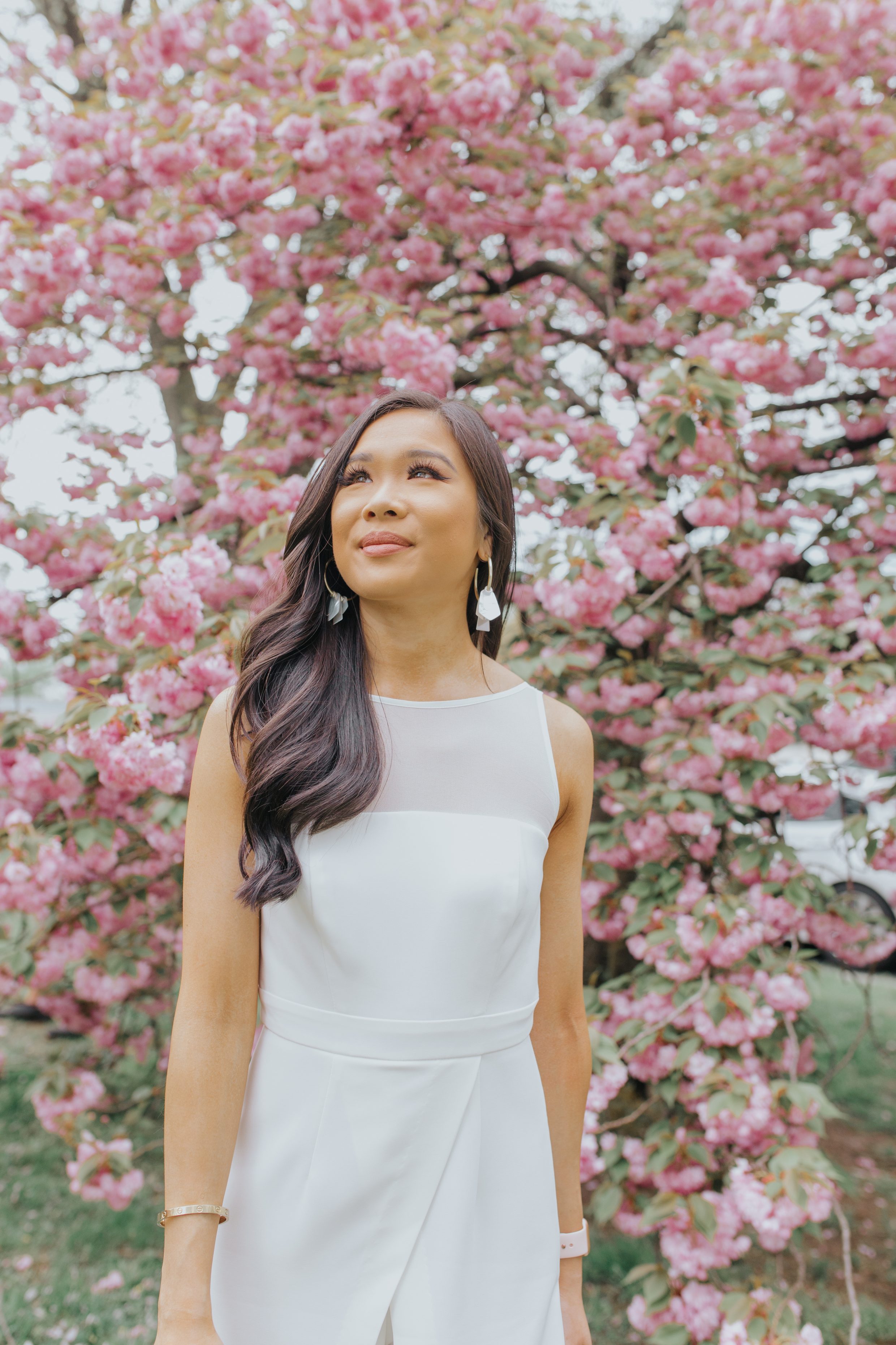 Hoang-Kim wears a white statement jumpsuit amidst the cherry blossoms in Washington, D.C.