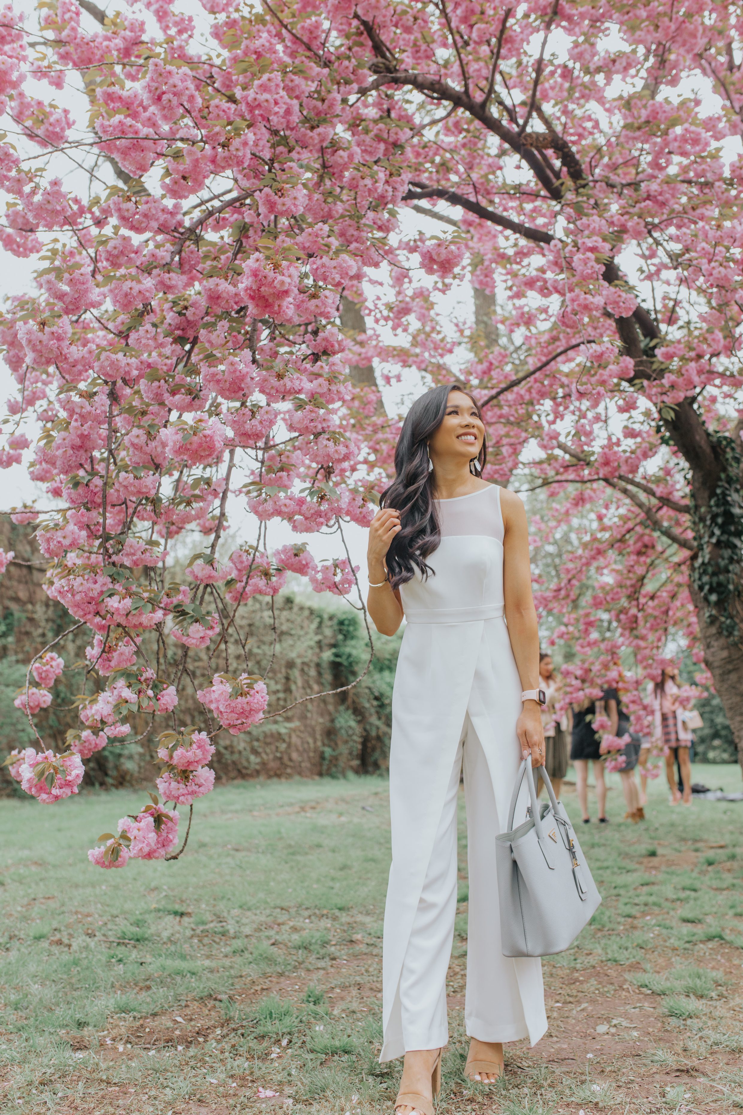 Hoang-Kim wears a white statement jumpsuit amidst the cherry blossoms in Washington, D.C.