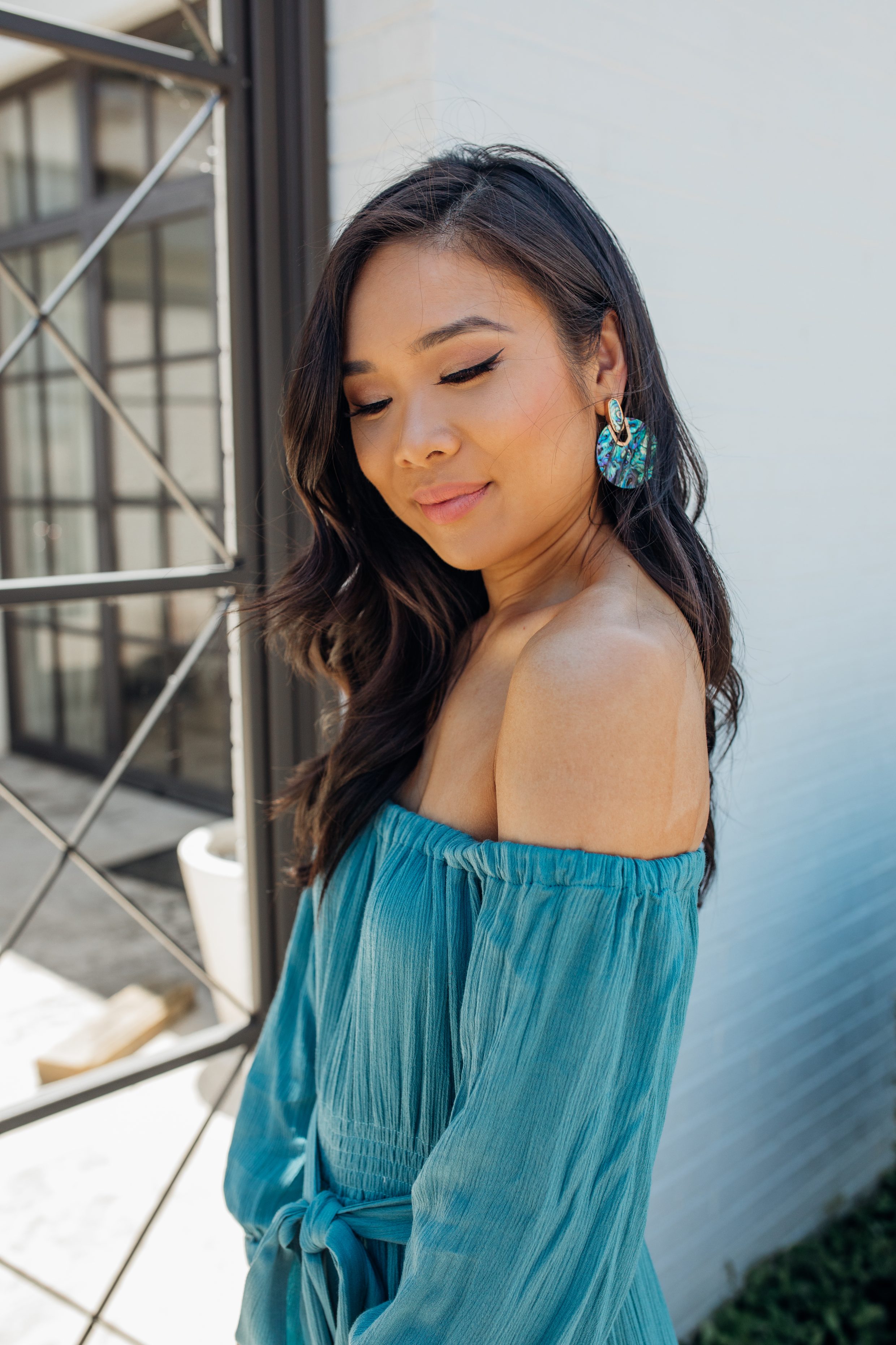 Blogger Hoang-Kim wears a teal off-the-shoulder maxi and Kendra Scott Didi Earrings in Abalone Shell