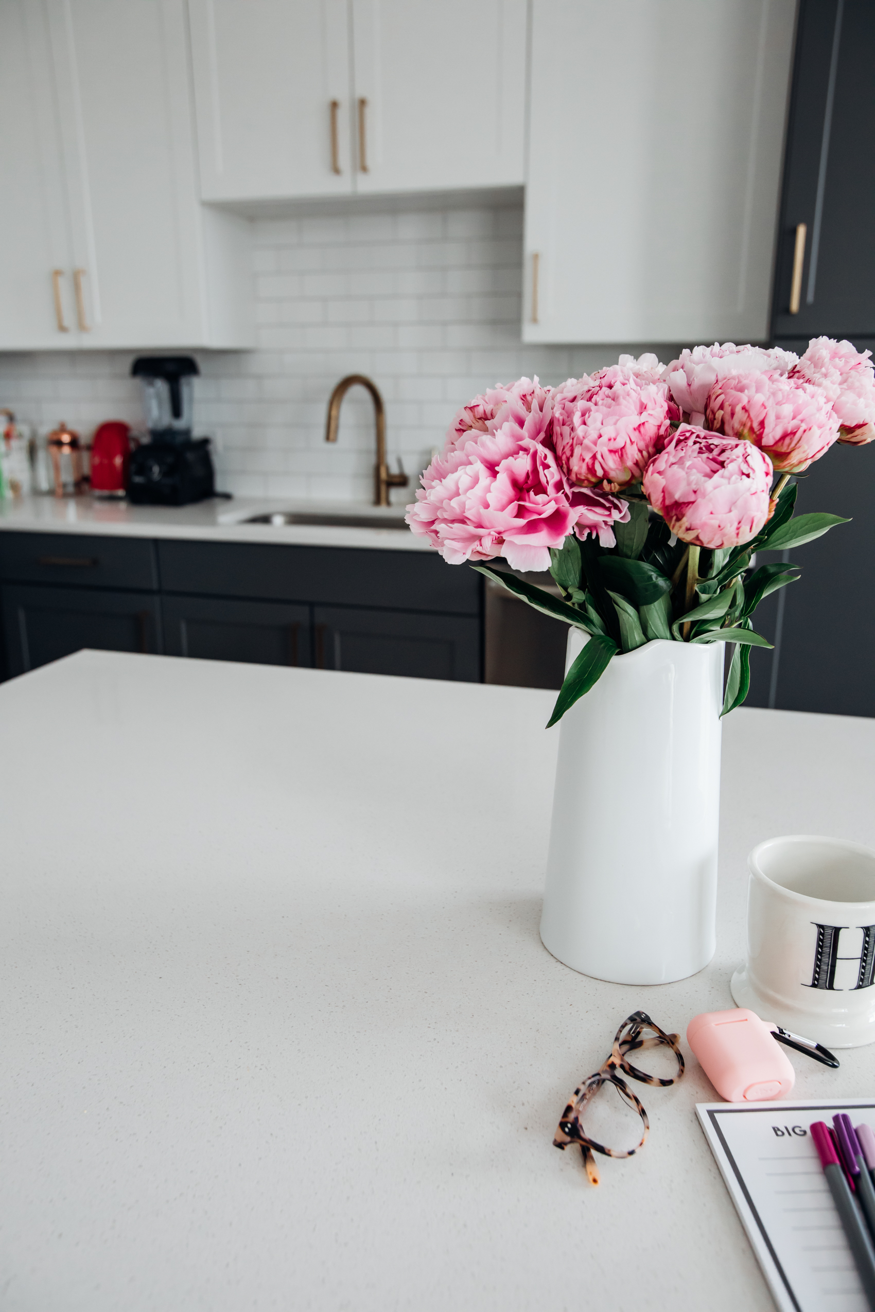 Dallas apartment with two-tone kitchen cabinets and gold hardware with bouquet of pink peonies
