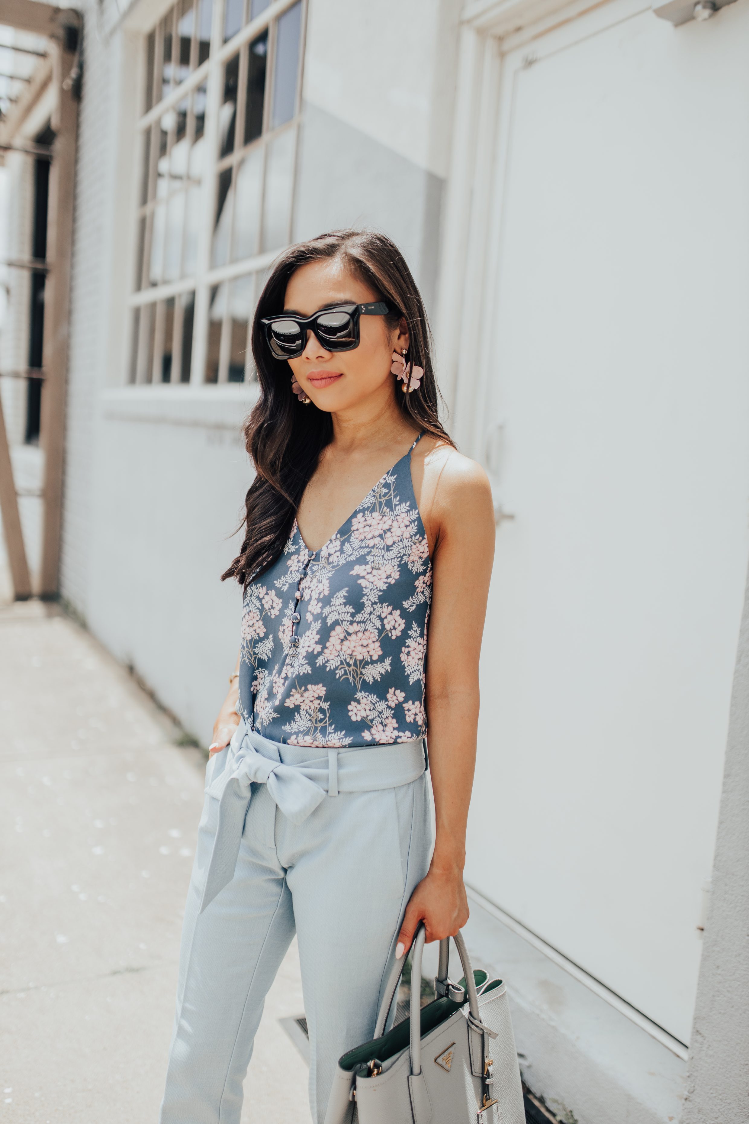 Petite blogger wearing a floral cami, tie waist pants and floral drop earrings outside a local dallas coffee shop