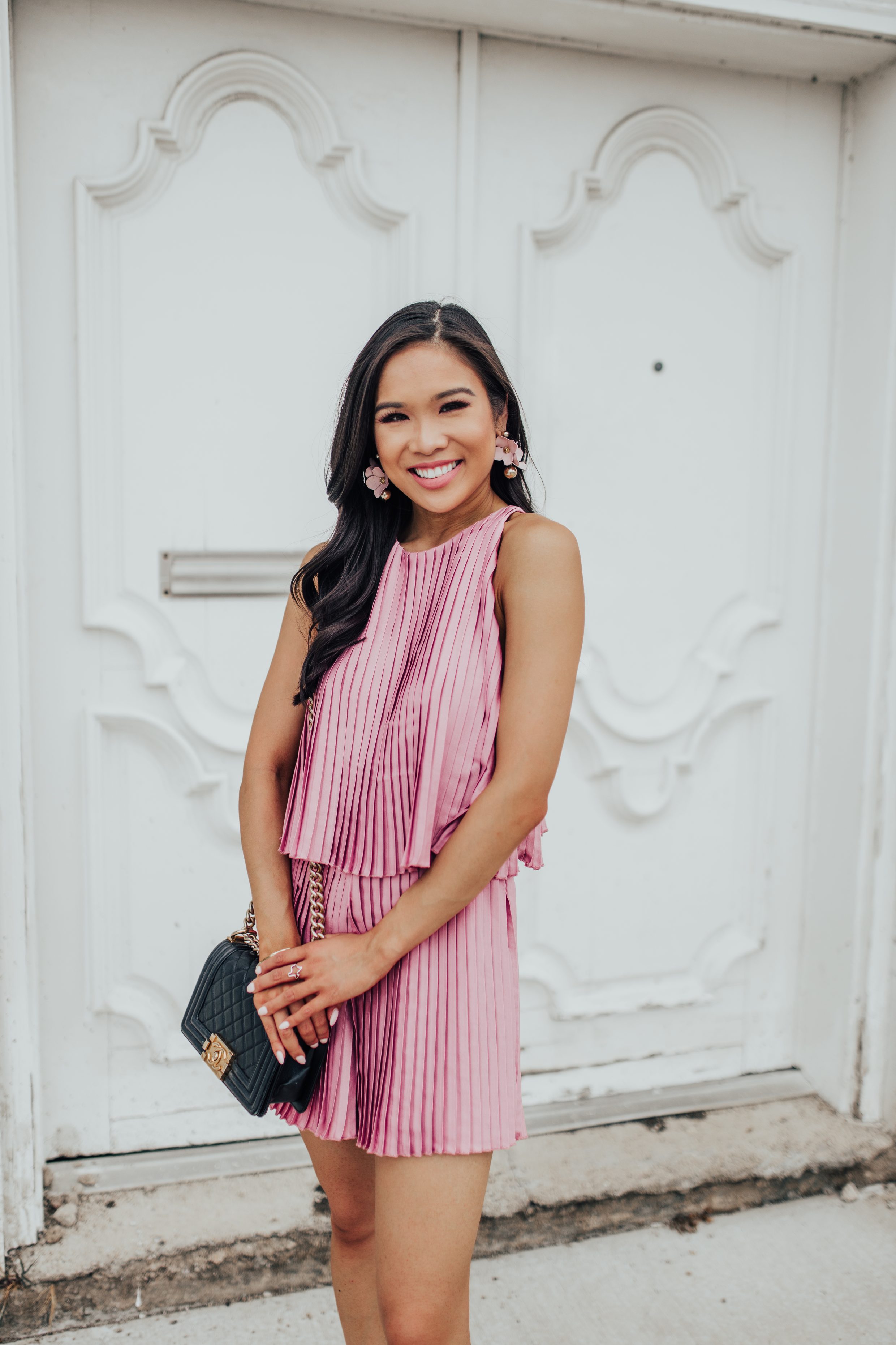 Petite blogger wears a pleated pink lovers + friends romper with olive + piper sarahi earrings in mauve