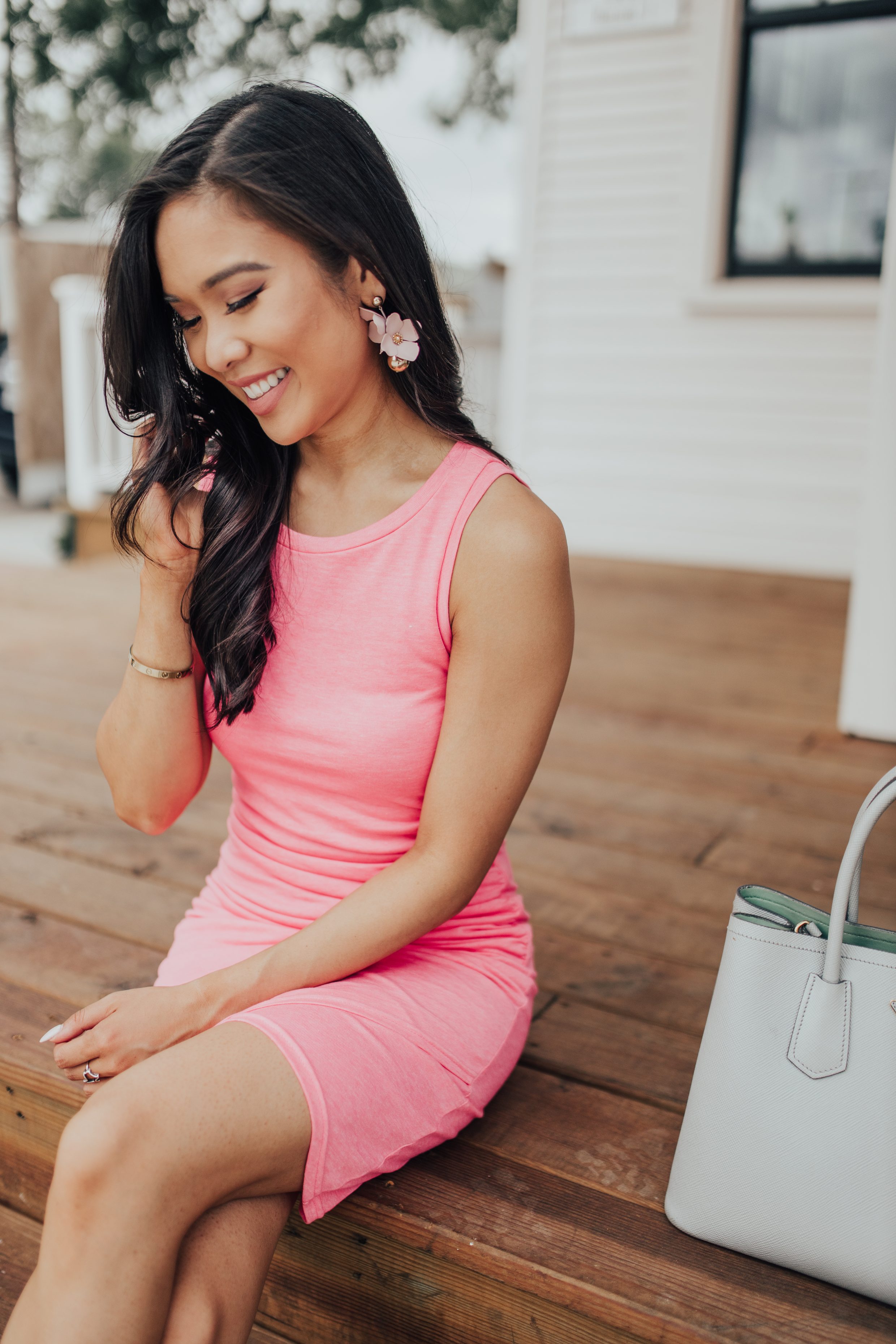 Petite blogger Hoang-Kim wears a ruched bodycon dress with floral earrings and white sneakers in Bishop Arts Dallas