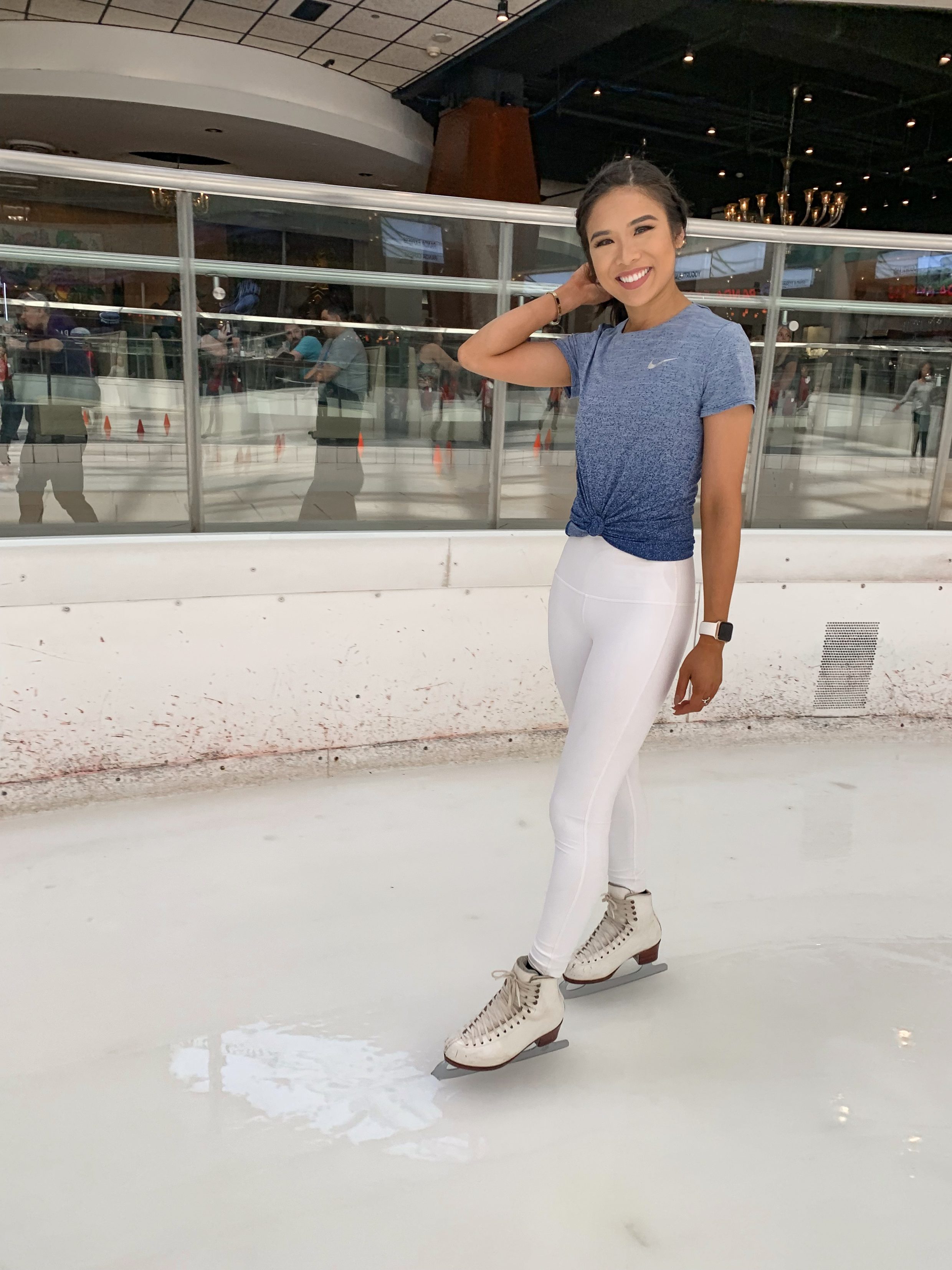 Petite blogger wears an Ice skating outfit featuring Nike blue dri-fit shirt and Lululemon white high waisted leggings