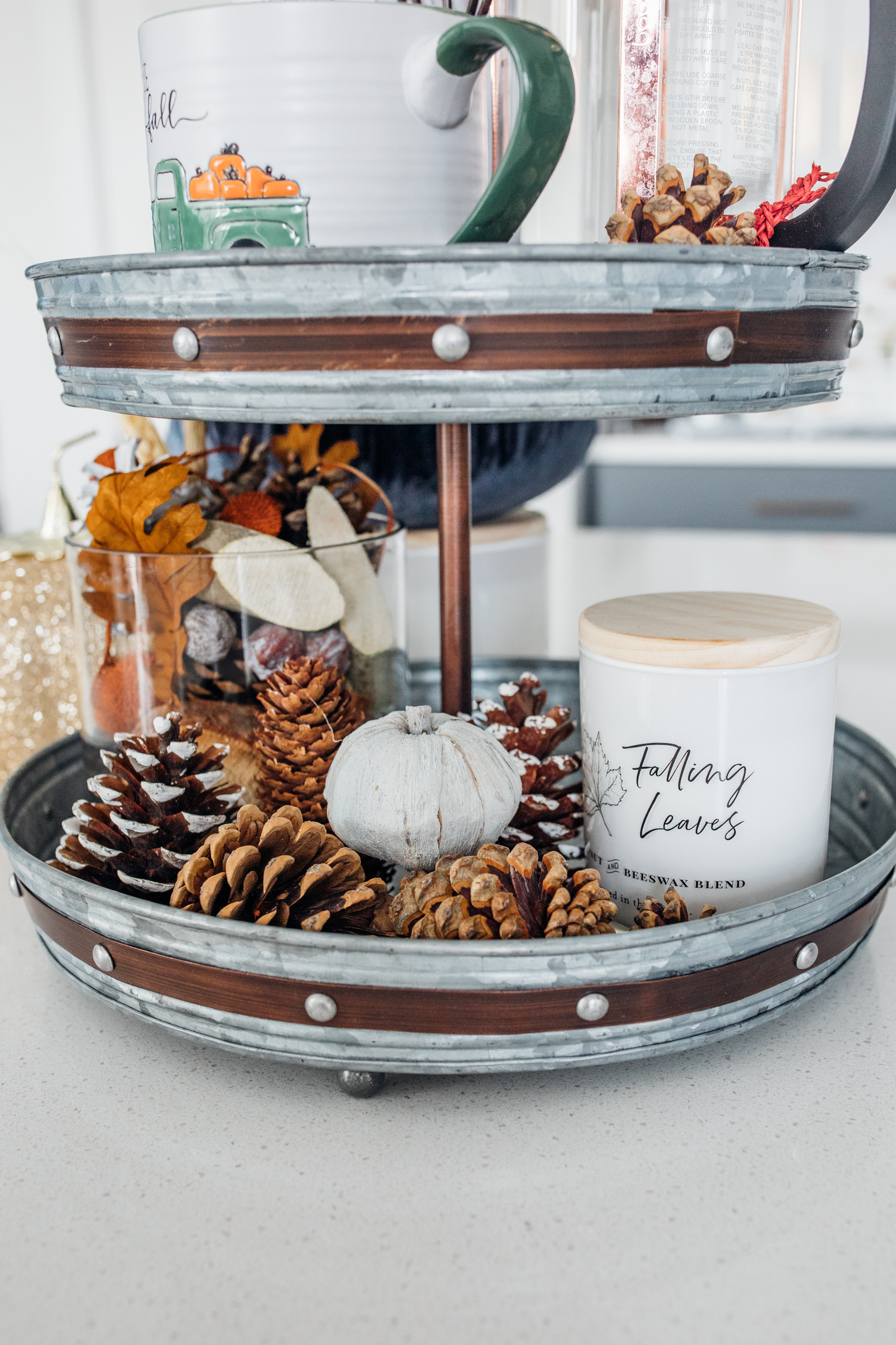Fall kitchen table decor with pinecones, pumpkins and candles creating a centerpiece