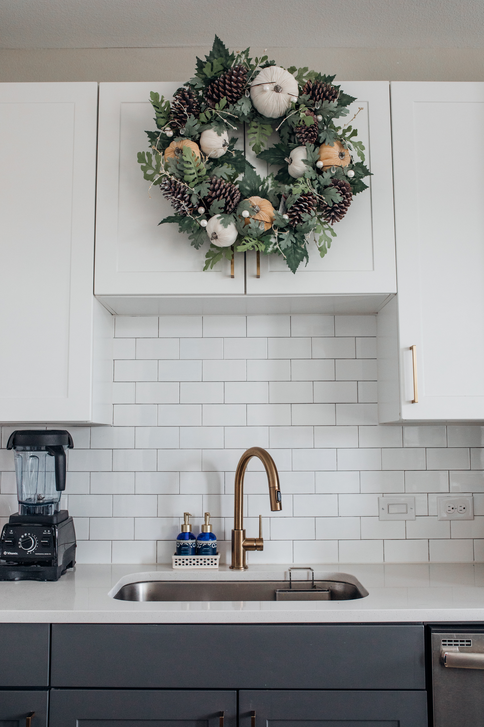 Velvet pumpkin and pinecone wreath for fall kitchen decor above a farmhouse sink with gold faucet