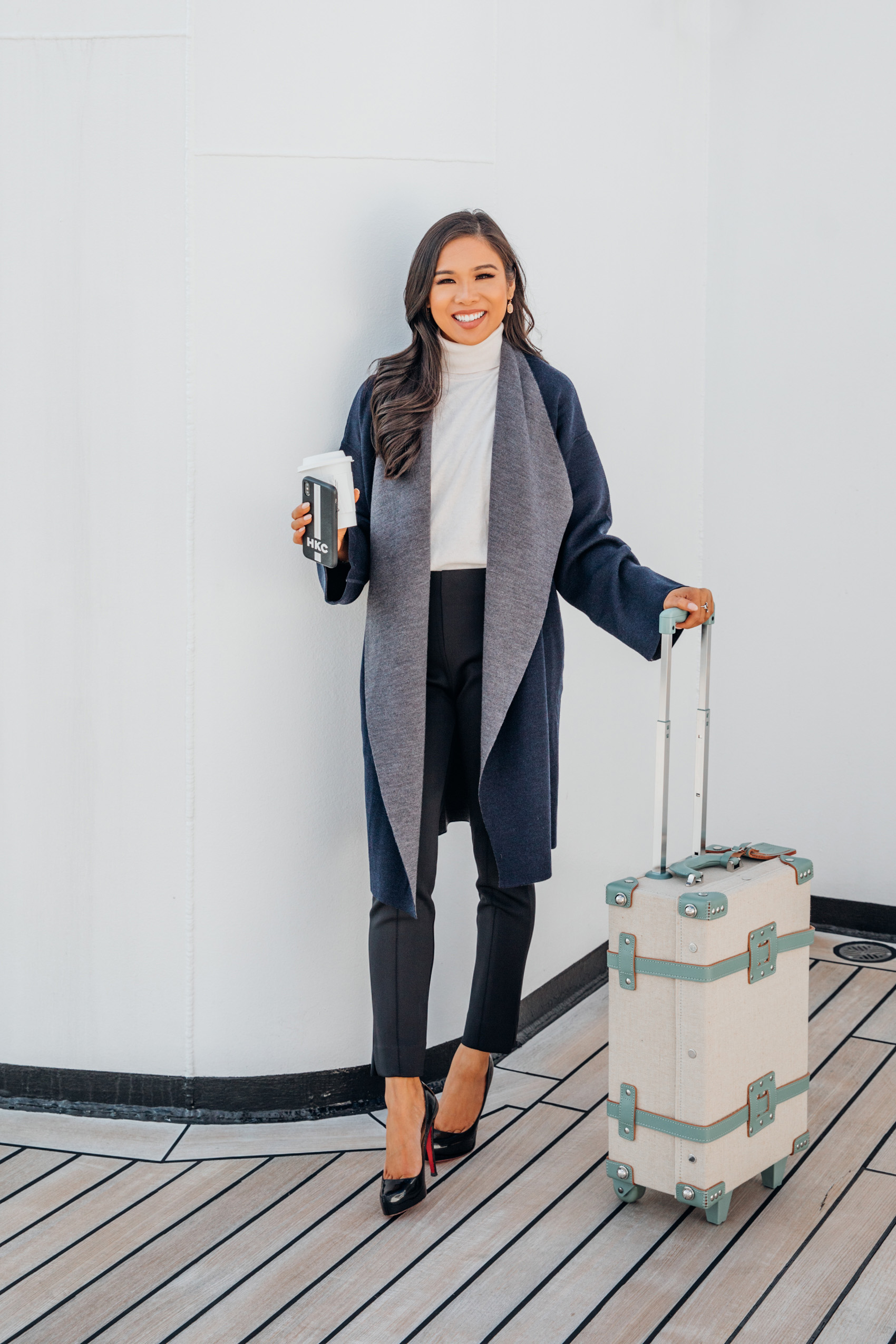 Blogger Hoang-Kim shares work travel outfits with a sleeveless turtleneck, merino wool coat and black pants