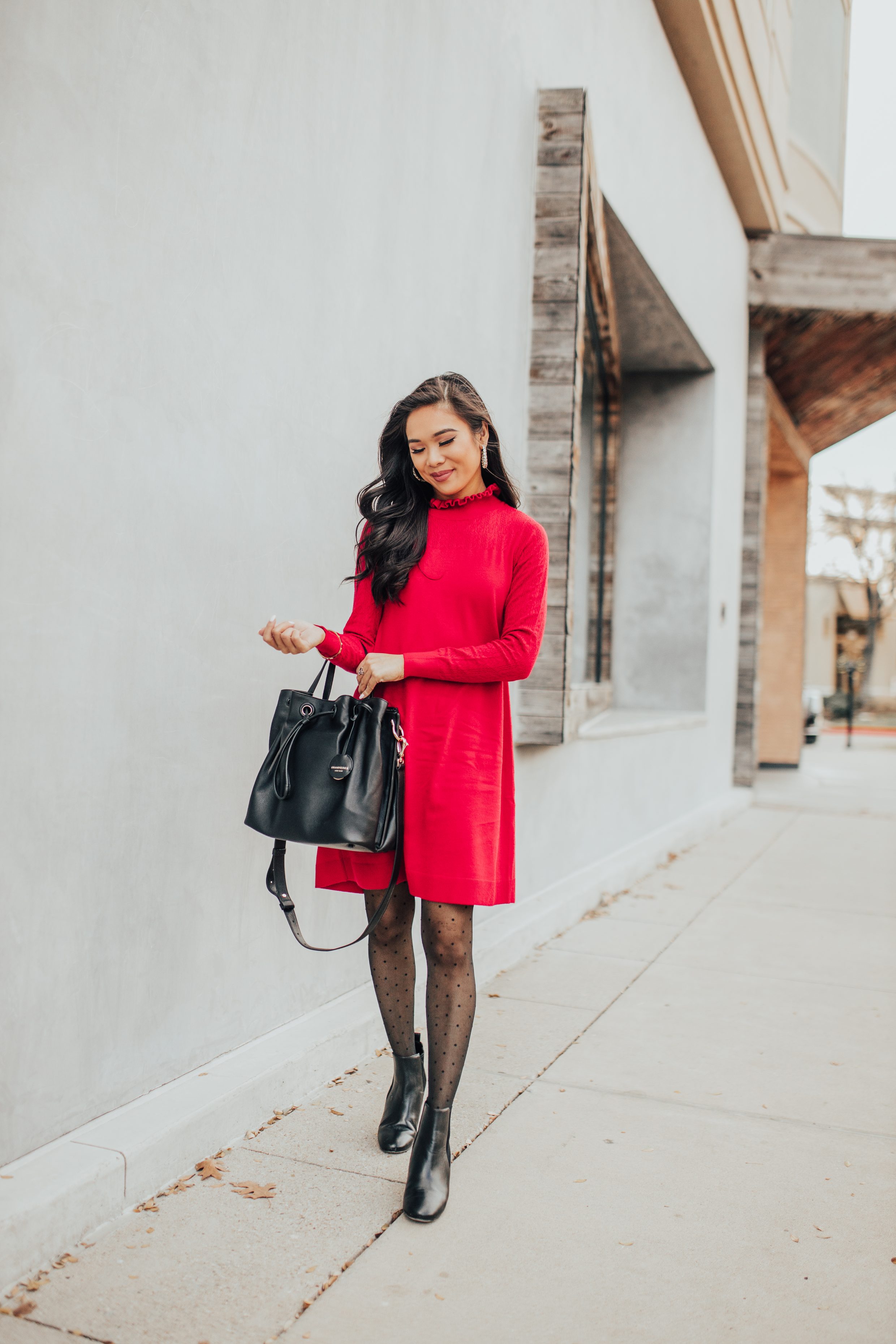 holiday outfit ideas with a red sweater dress, polka dot tights, bucket bag and hoop earrings