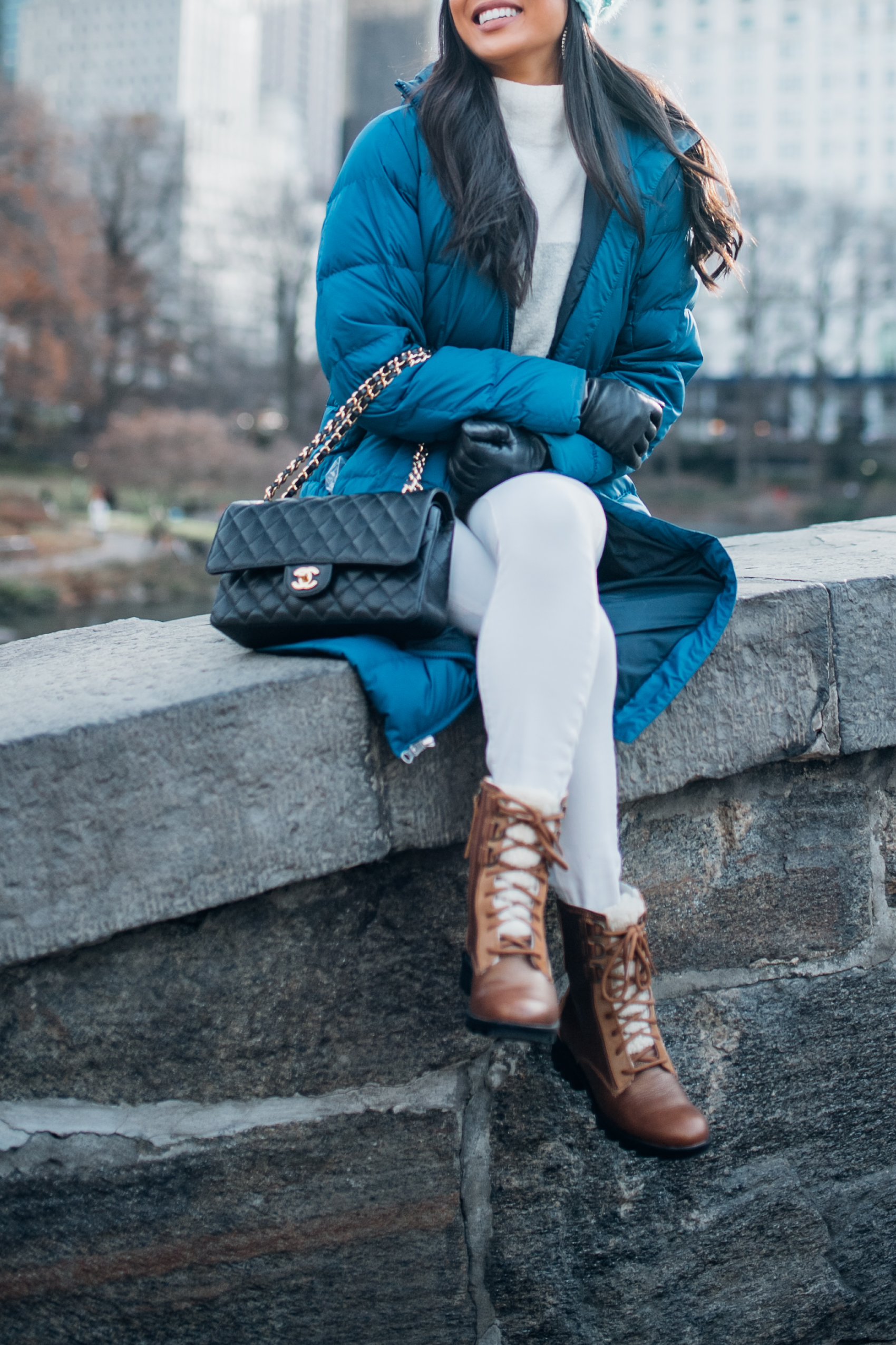 Winter outfits for the cold with a blue parka, brown boots, white jeans and Chanel double flap
