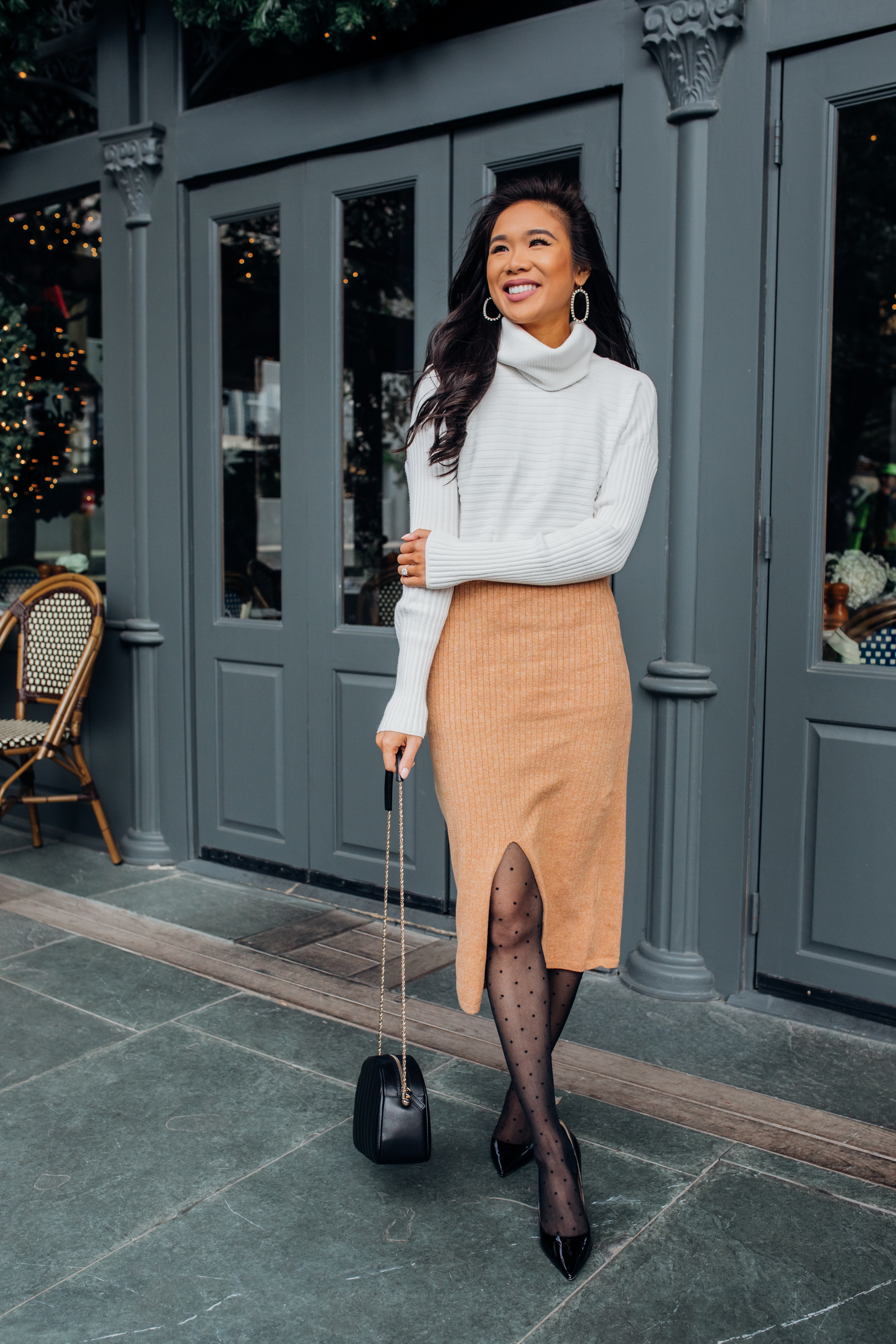 Winter work wear outfit with a Chico's white turtleneck sweater, Free People Skyline Midi ribbed skirt in caramel heather, Falke polka dot tights, M Gemi heels, Kendra Scott earrings on Dallas fashion blogger Hoang-Kim Cung