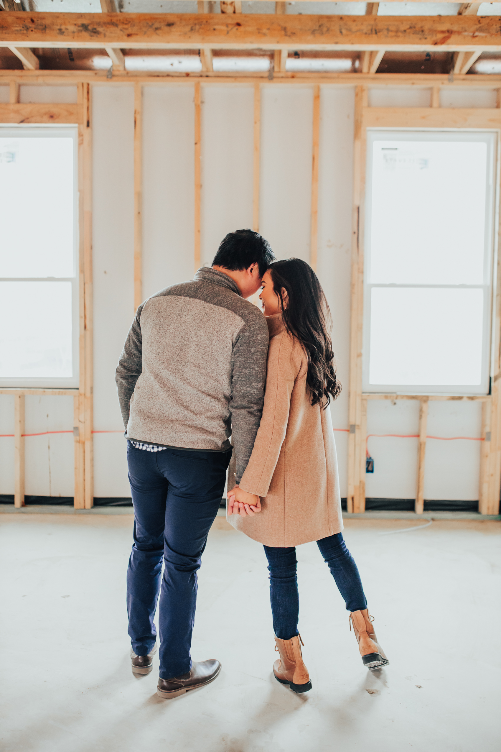 Asian couple in their soon-to-be master bedroom of a one-story house in Dallas, Texas after the framing stage