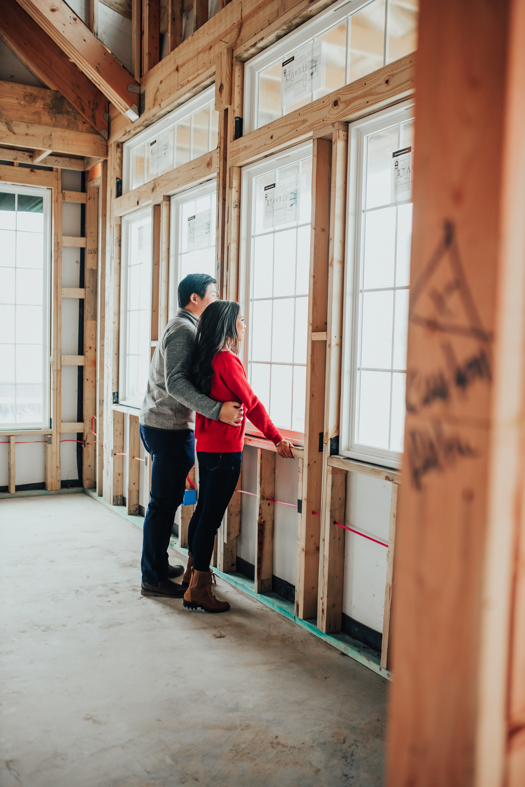Couple looking out the window of their one-story house during the pre drywall framing stage