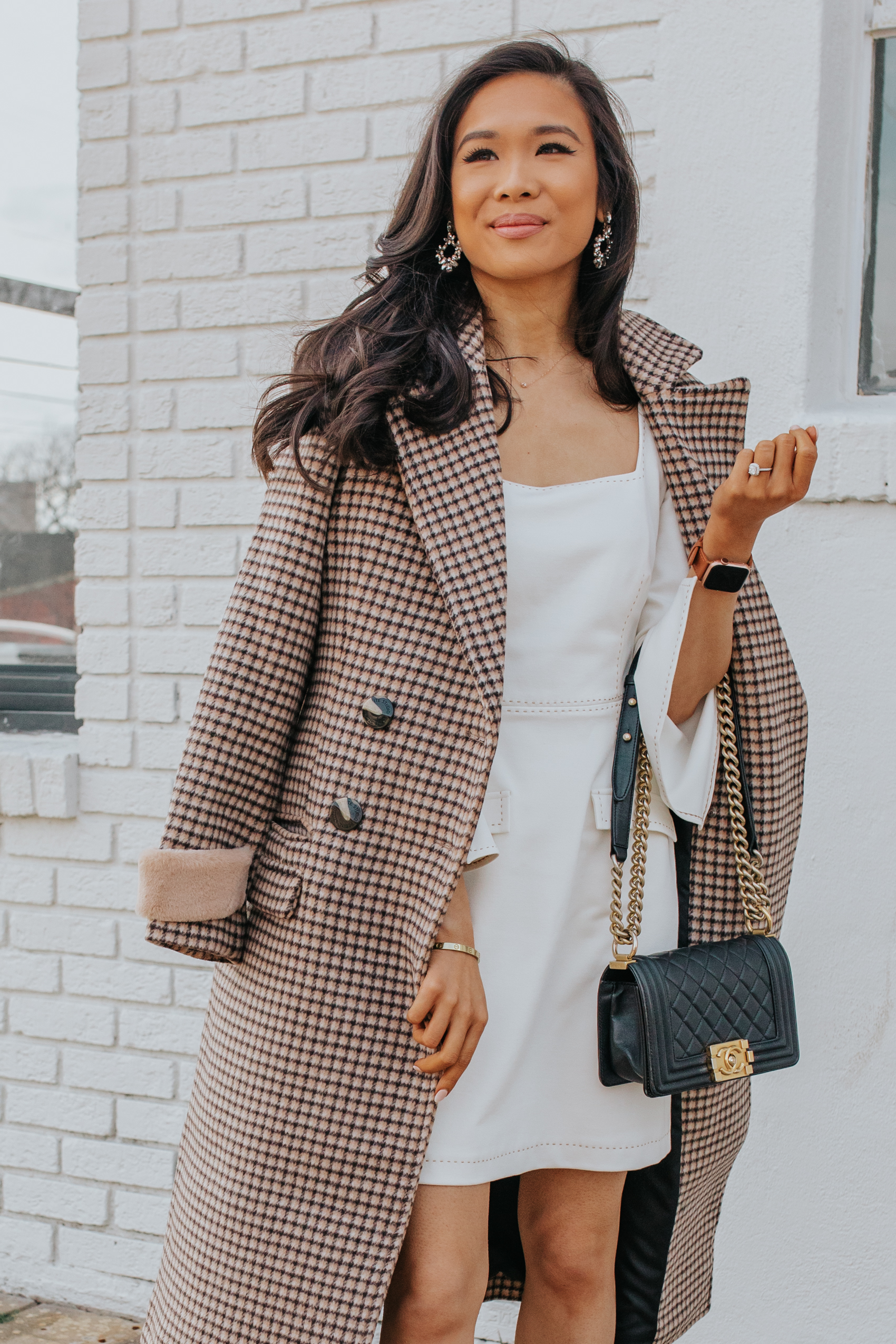 Asian woman wearing a plaid coat made of wool from ethical fashion brand petite studio nyc, white dress and Chanel Boy Bag size small